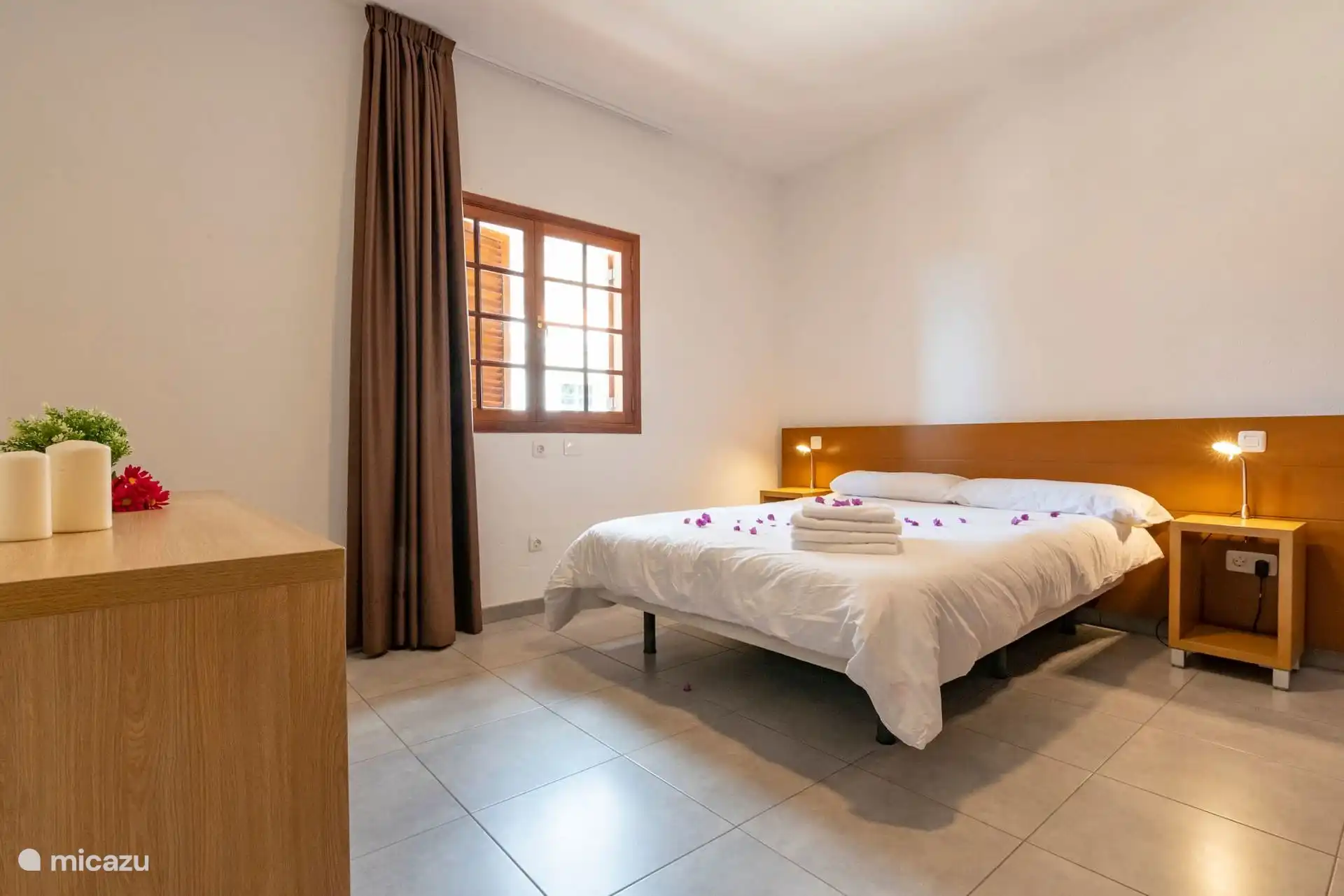 Schlafzimmer mit Doppelbett, Kommode und Fenster mit Holzfenster.