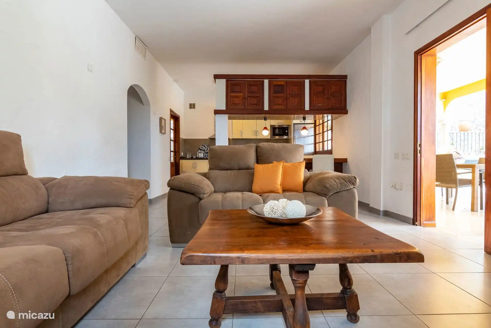 Das Wohnzimmer, mit der Küche hinten und dem Ausgang zur Veranda rechts.