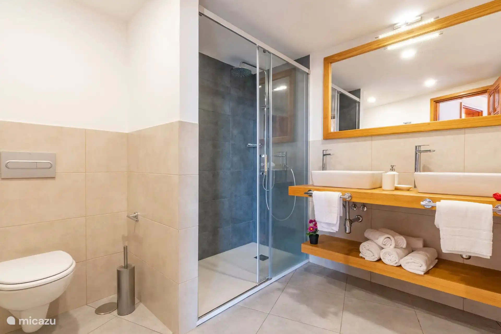 Bathroom with glazed shower and two sinks on wooden countertops.