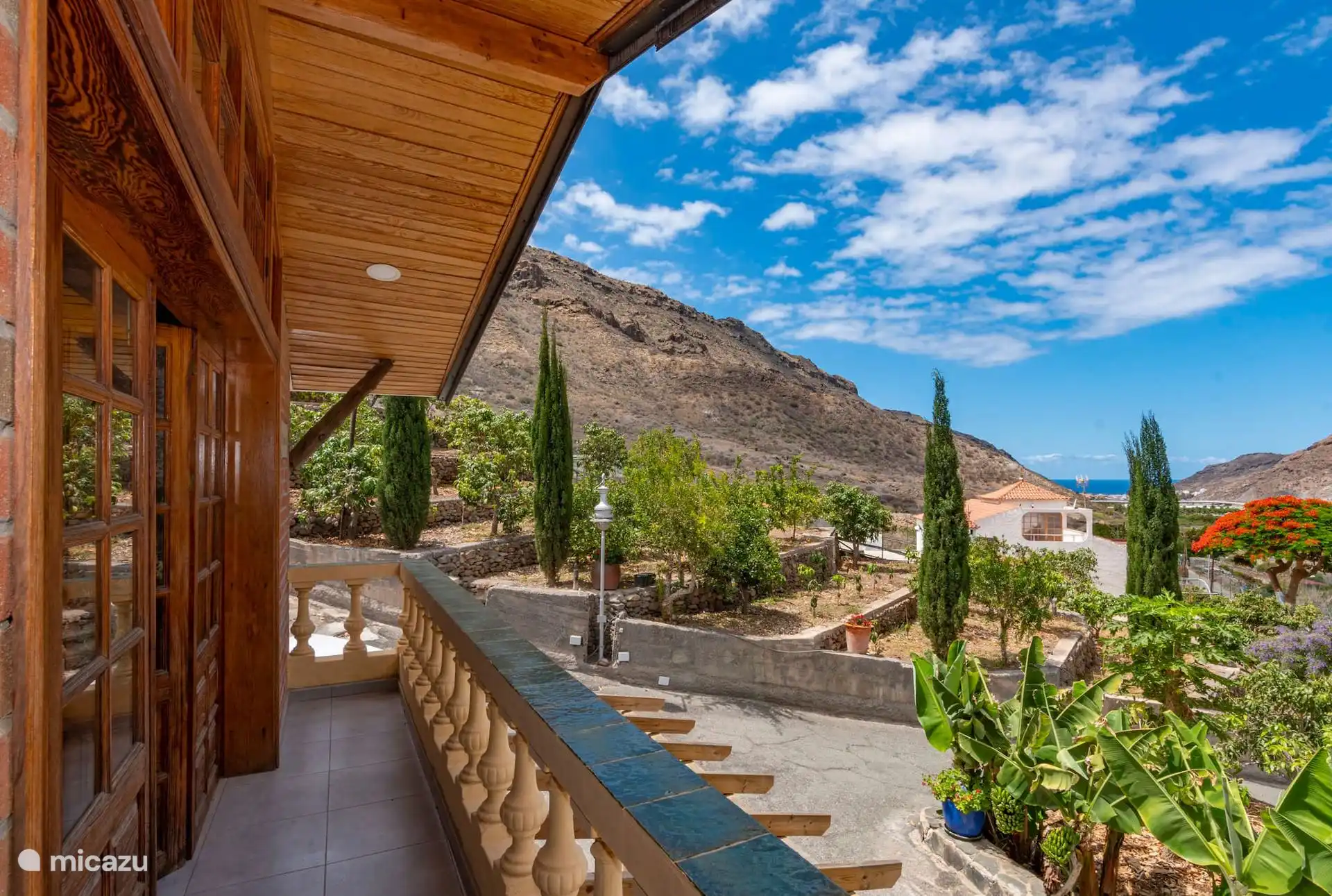Wooden balcony with balustrade, over the fruit trees of the estate and with the sea in the background.