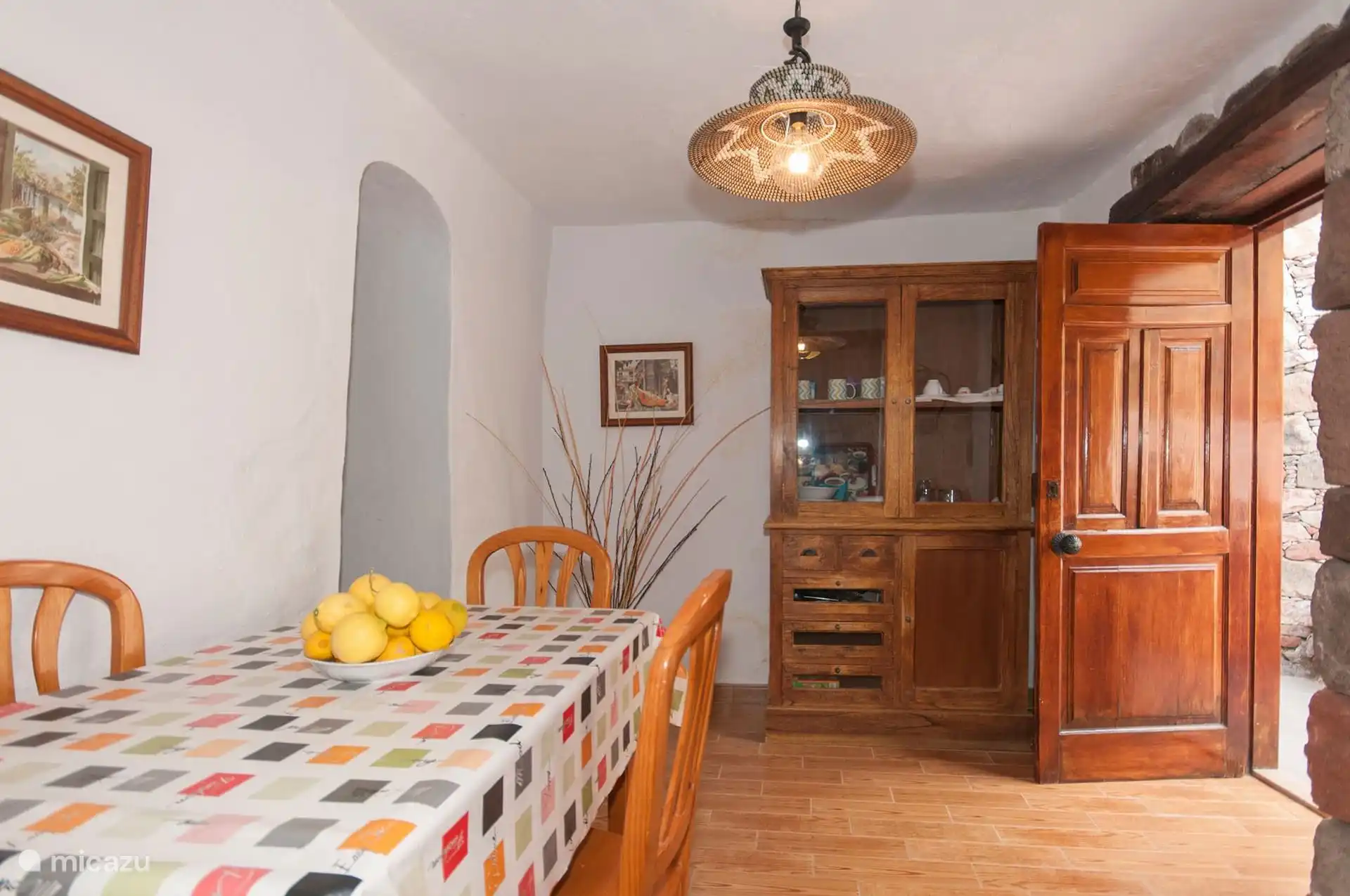 Eetkamer met tafel, stoelen en een houten vitrinekast.