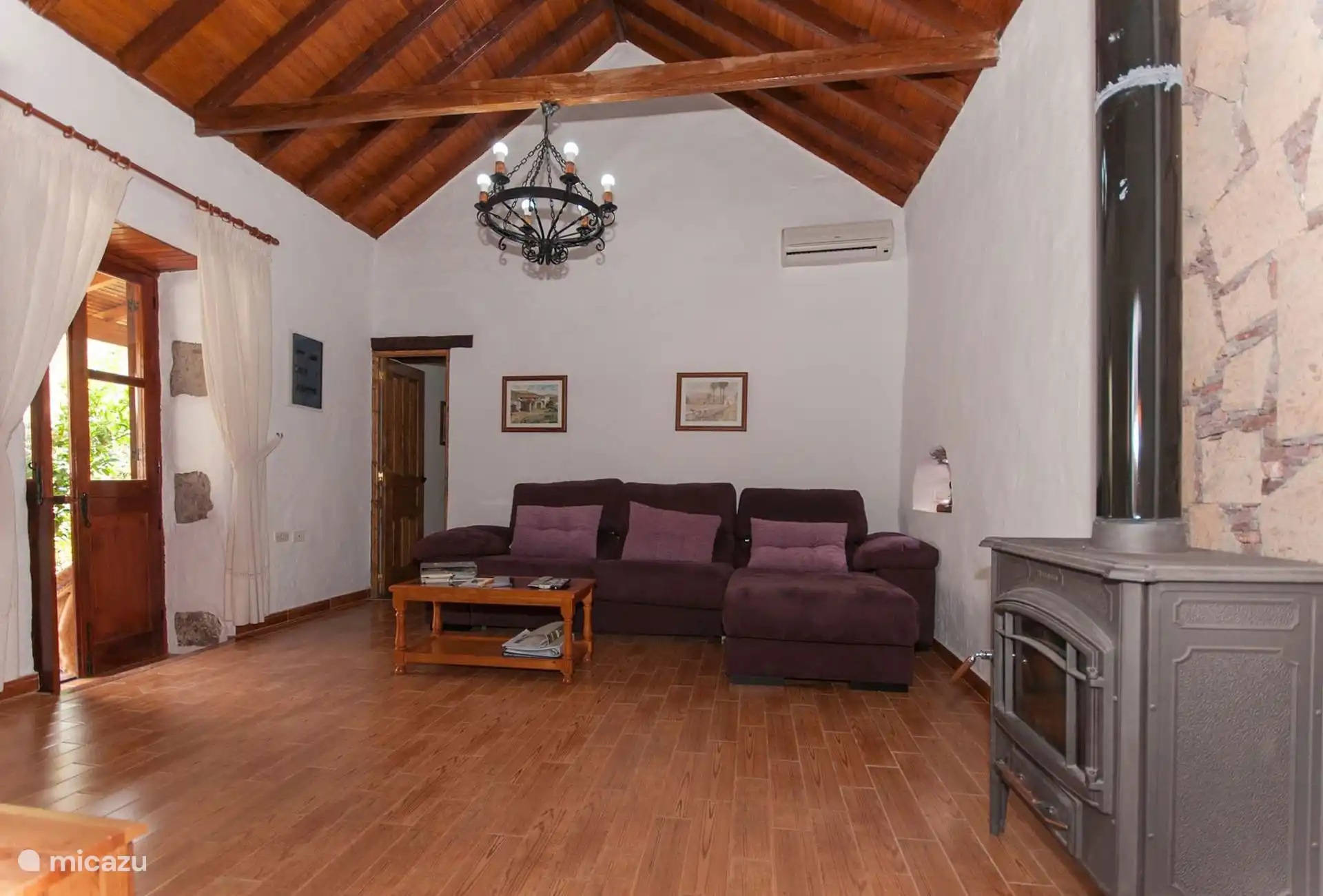 De woonkamer, met airconditioning, houtkachel en toegang naar buiten.