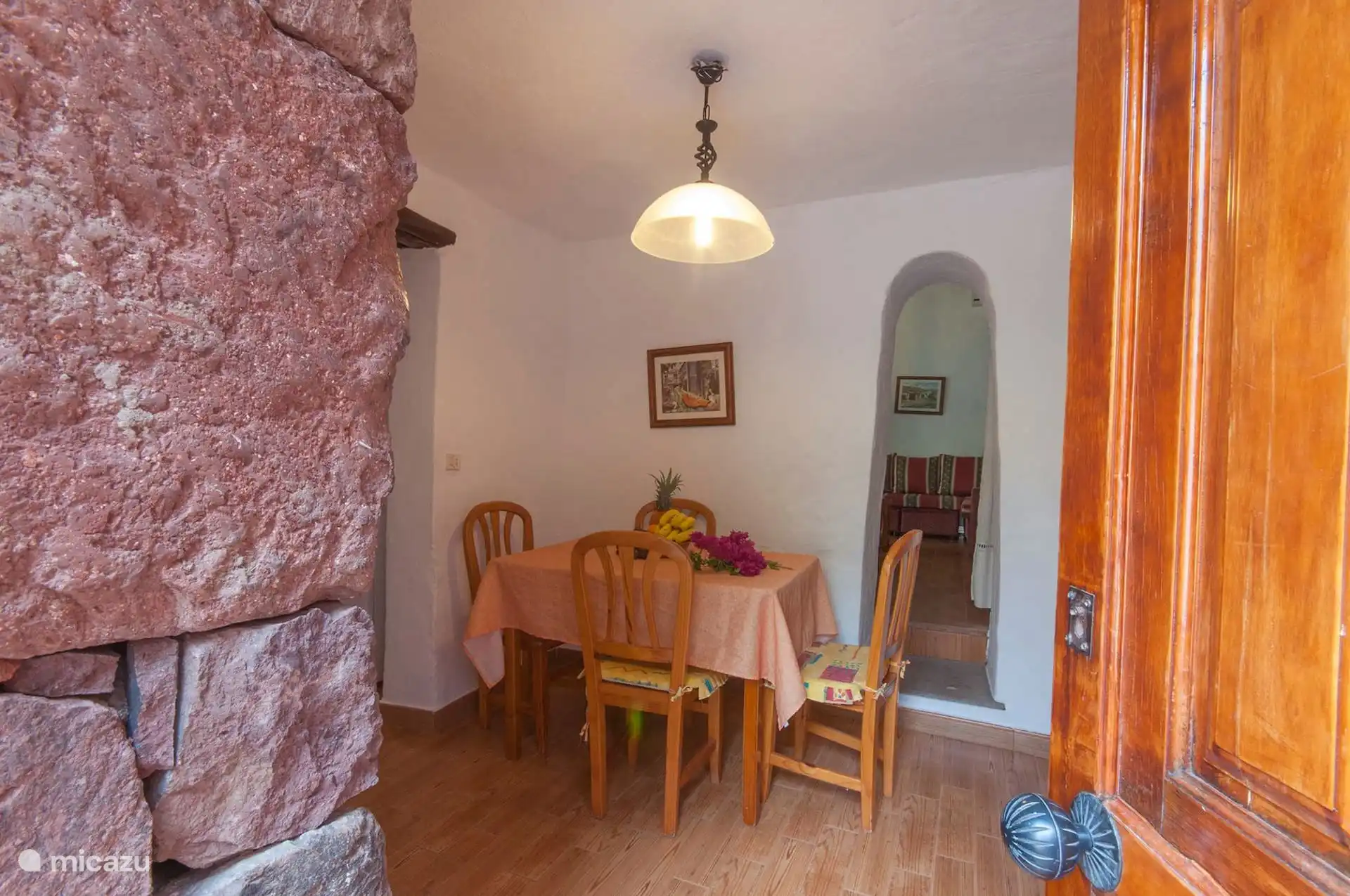 De eetkamer, met de originele rode stenen muur en de boog naar de woonkamer.