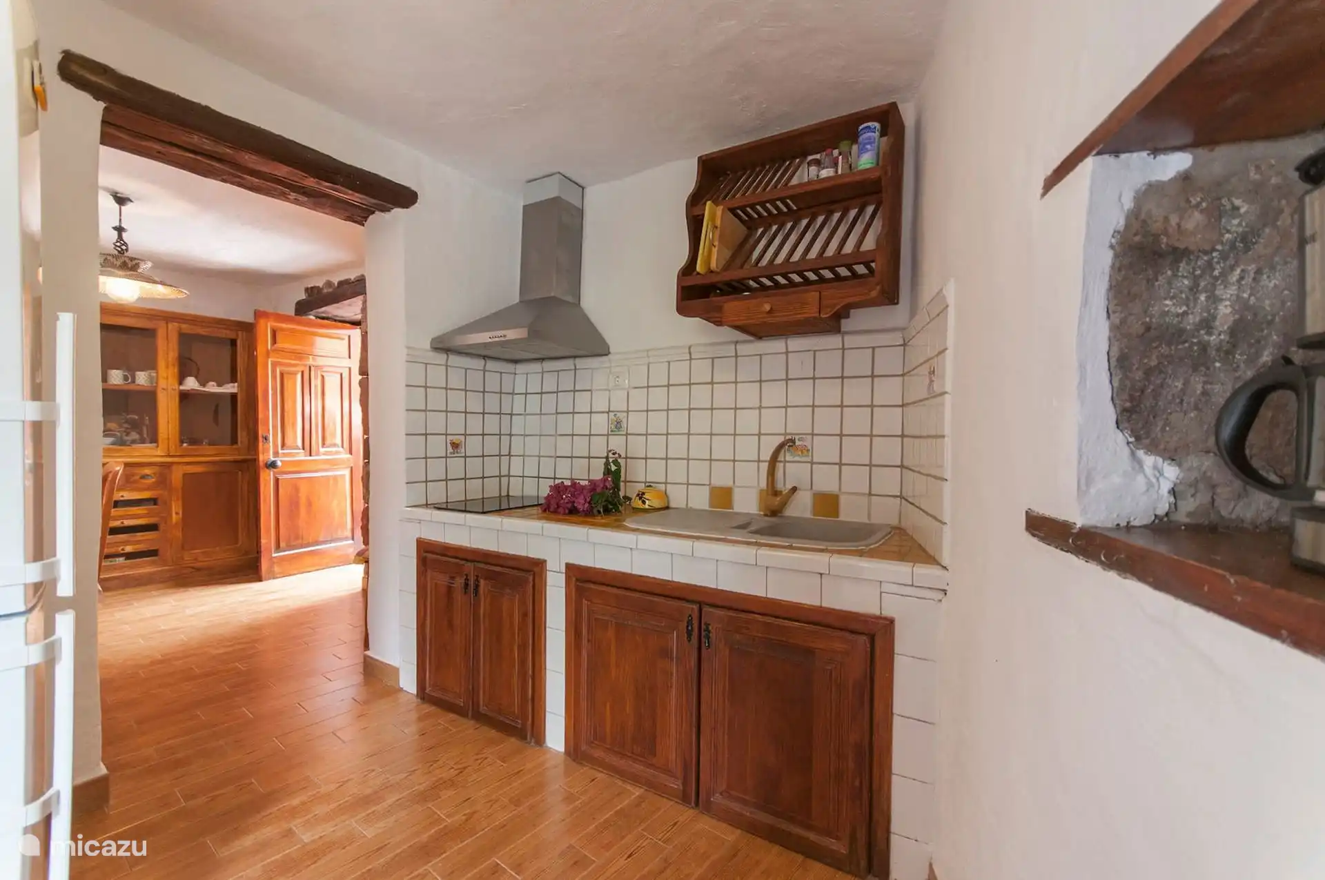 Keuken met keramische kookplaat, afzuigkap, gootsteen en houten afvoerafvoer.