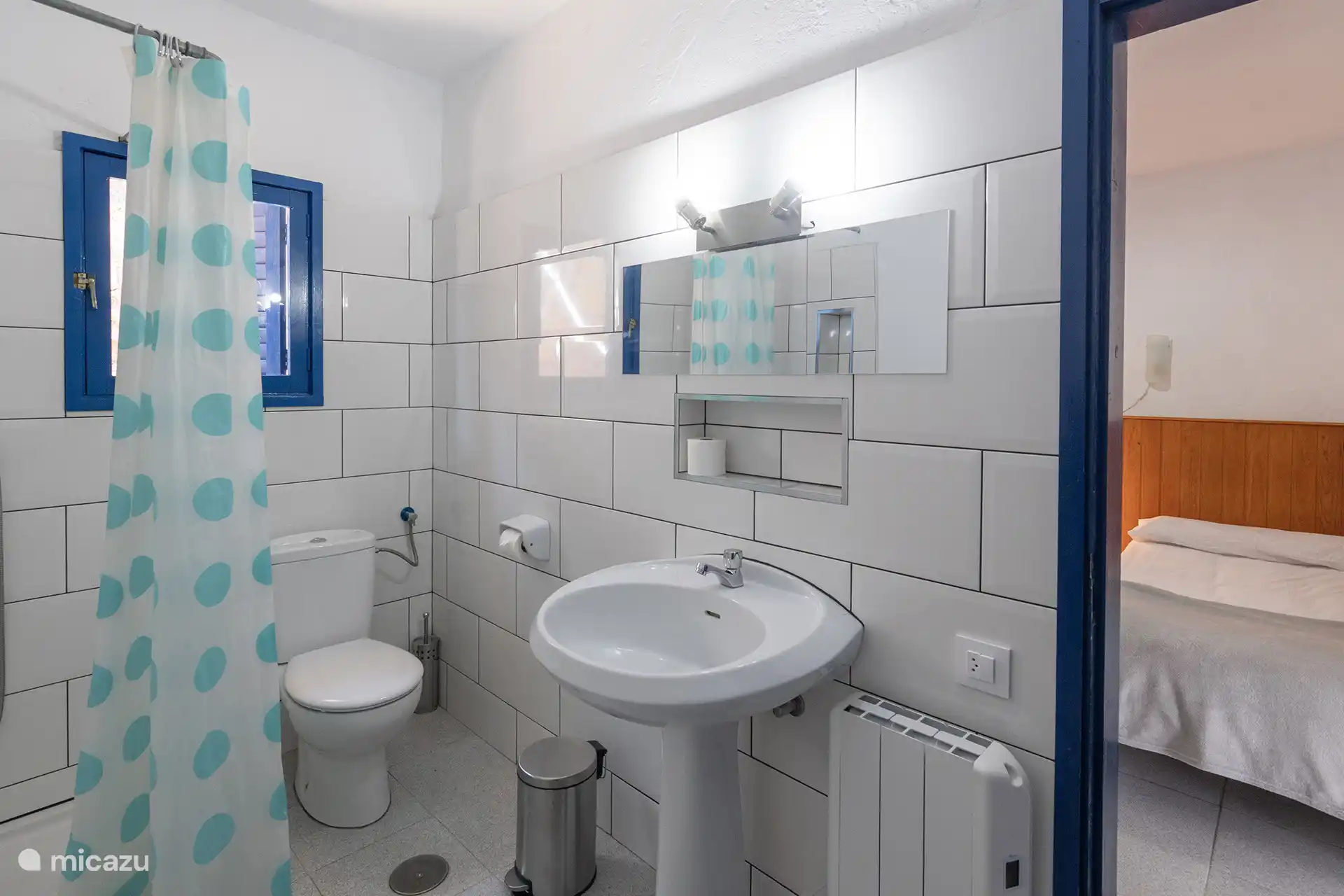 Badezimmer mit Dusche, Waschbecken und elektrischer Heizung.