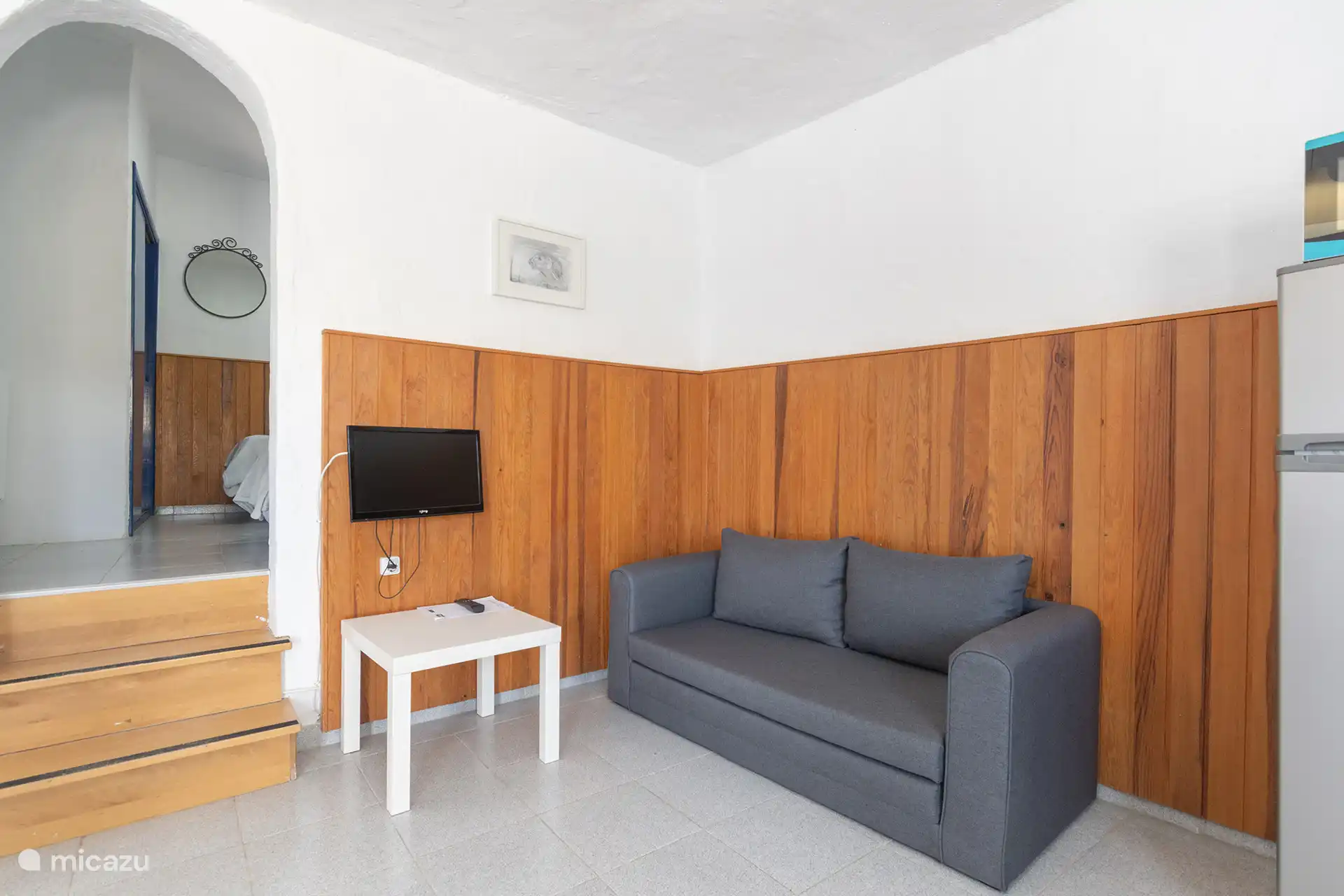 Sofa und Fernseher im Wohnzimmer, neben den Stufen zum Schlafzimmer.