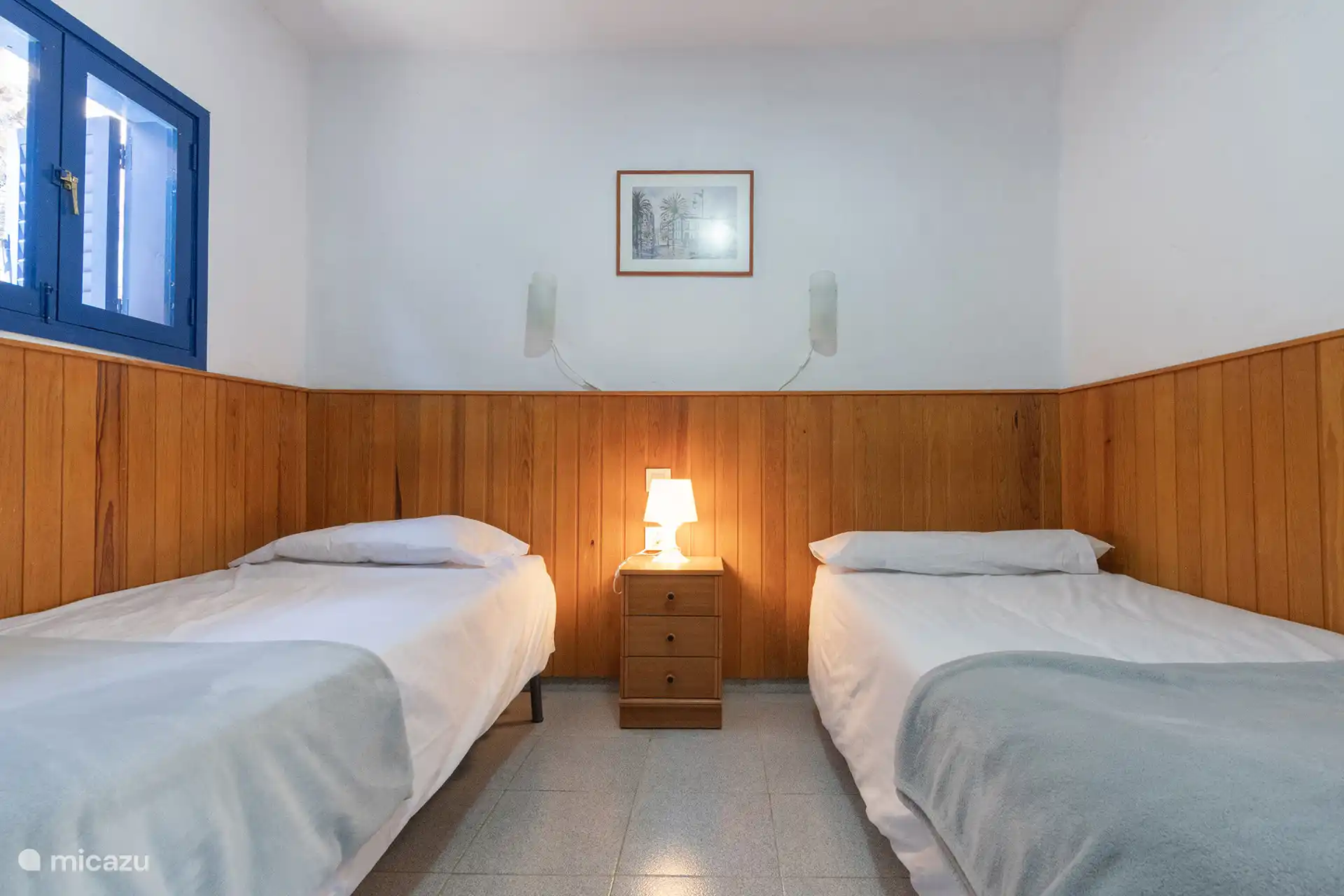 Schlafzimmer mit zwei Einzelbetten und blauem Fensterladen.