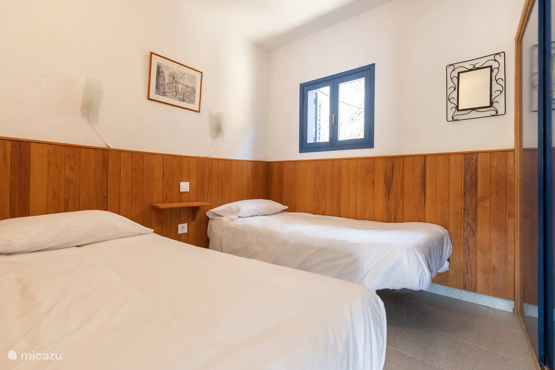 De slaapkamer, met een spiegel en een blauw luikenraam.