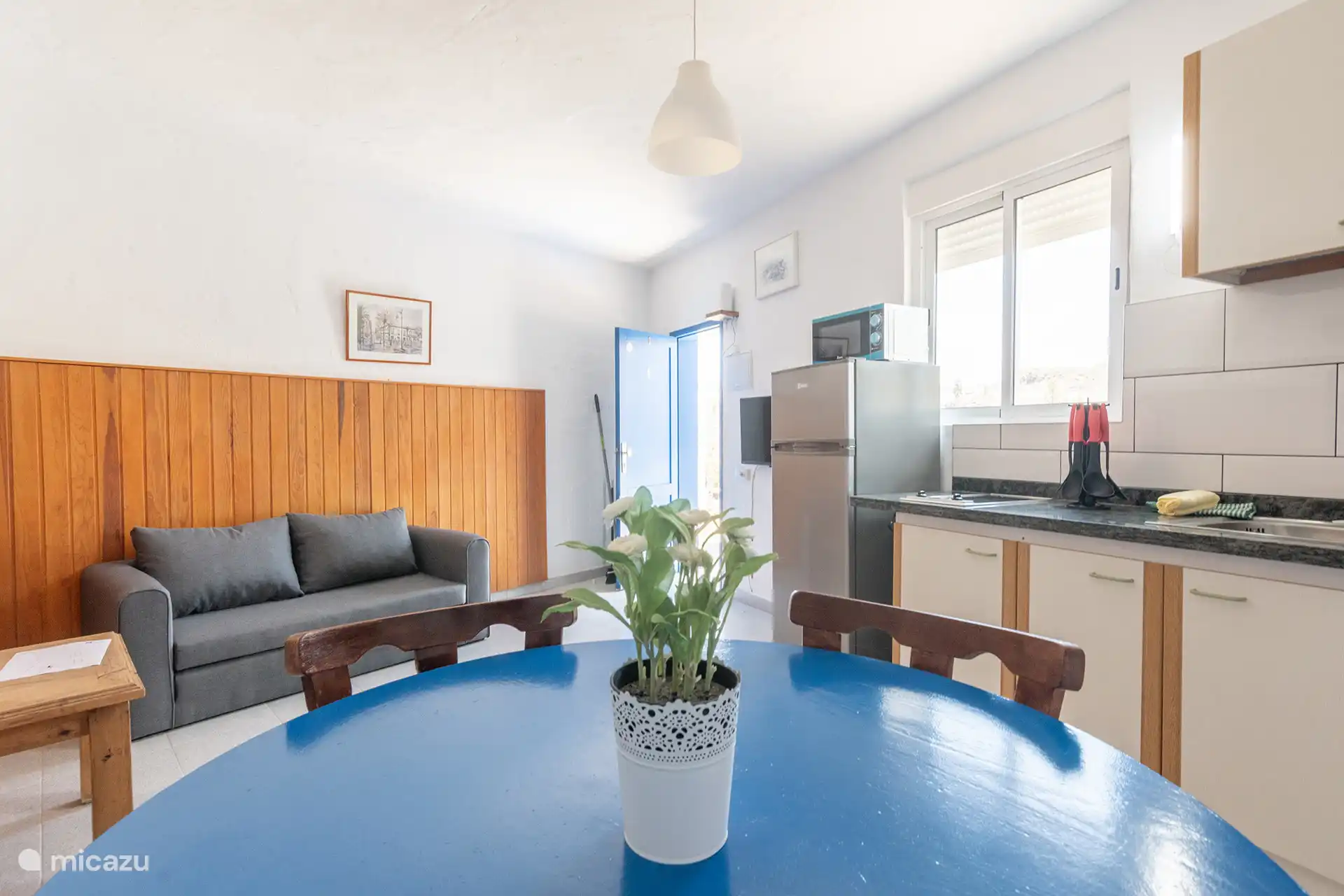 Living room with sofa bed, dining table and kitchen integrated at the back.