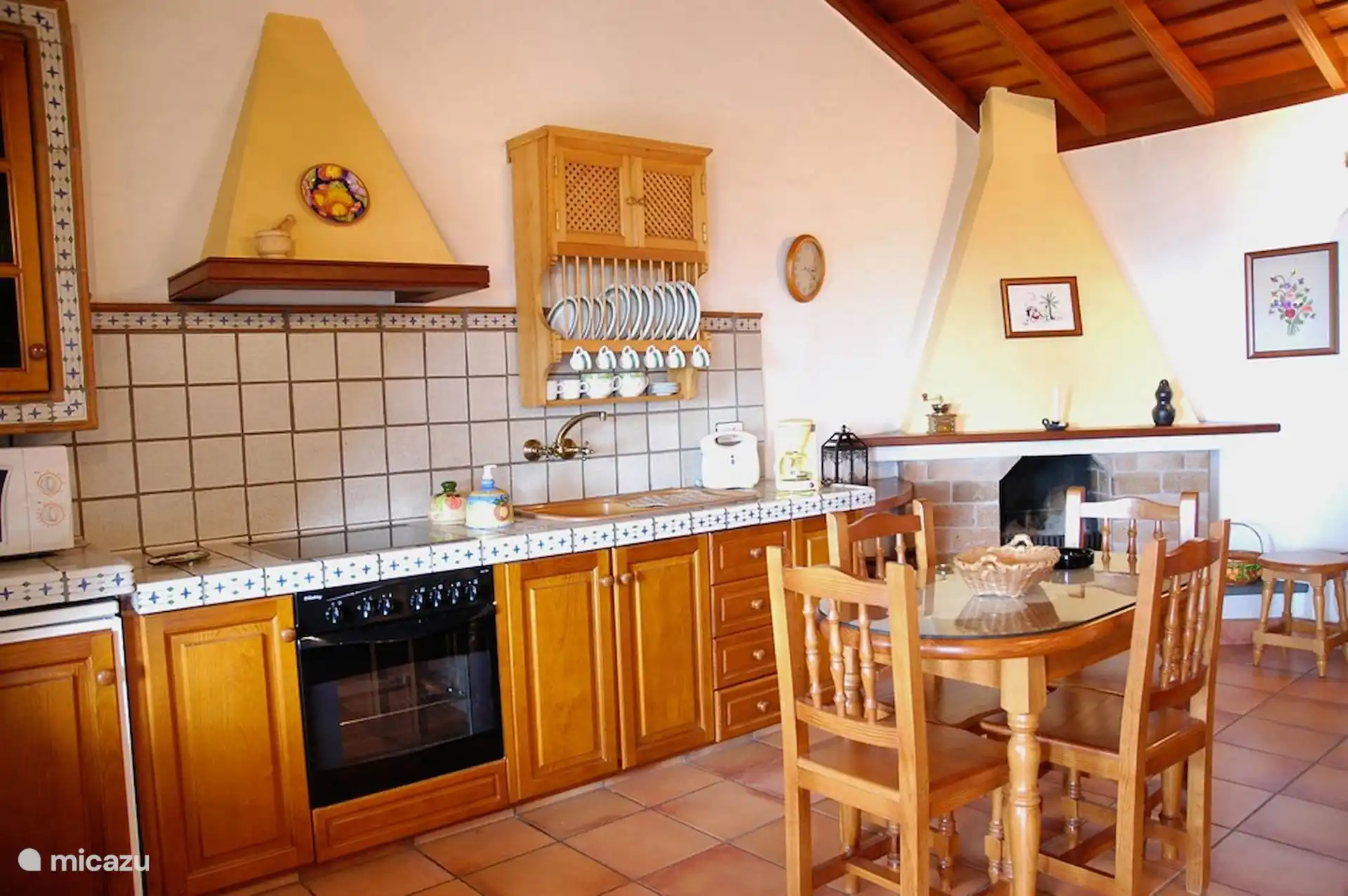 Küche und Esszimmer mit Steinkamin, Keramikherd, Ofen und Geschirr.