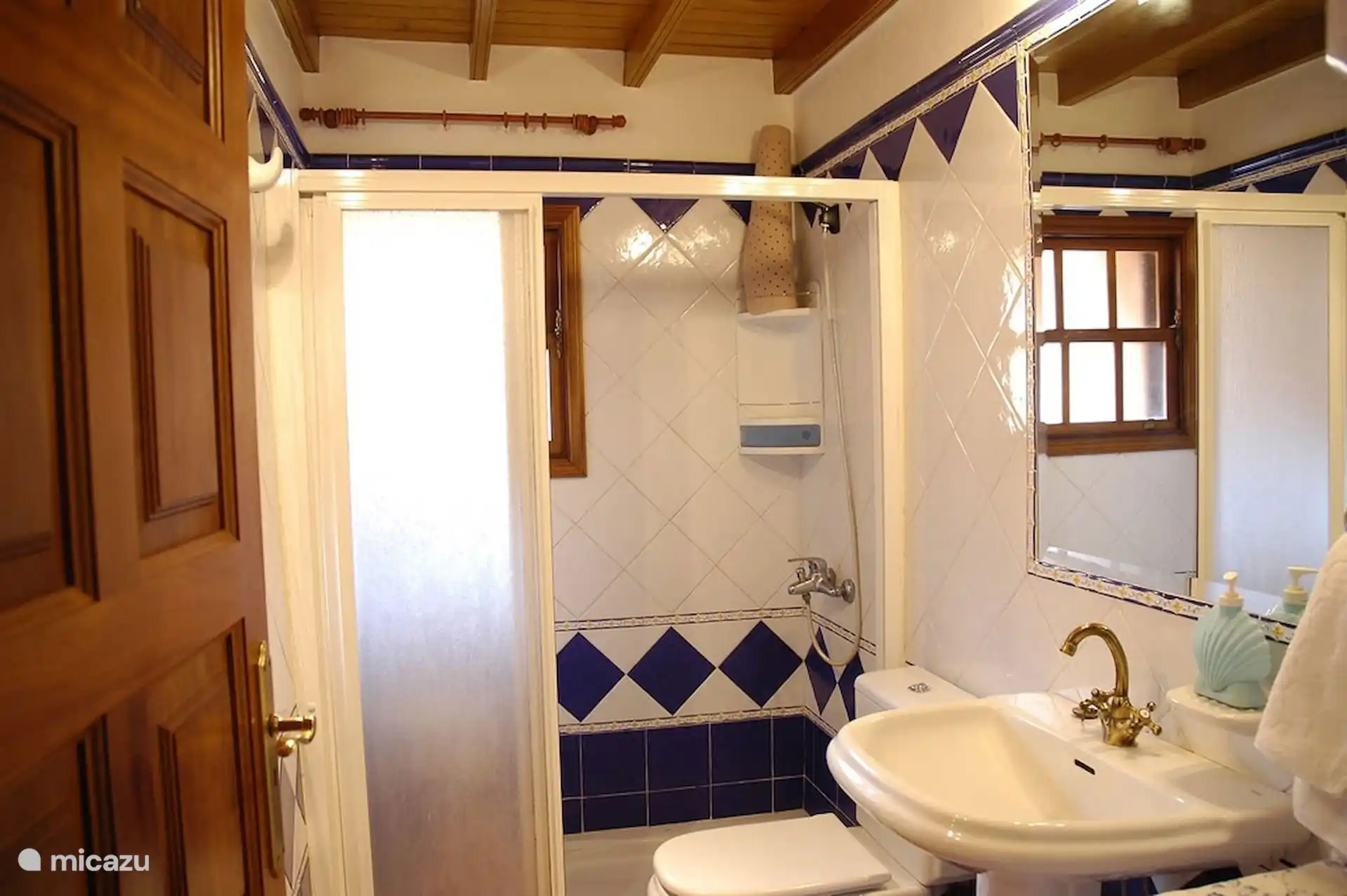 Badezimmer mit Duschgitter, weißen und kobaltblauen Fliesen und Fenster.