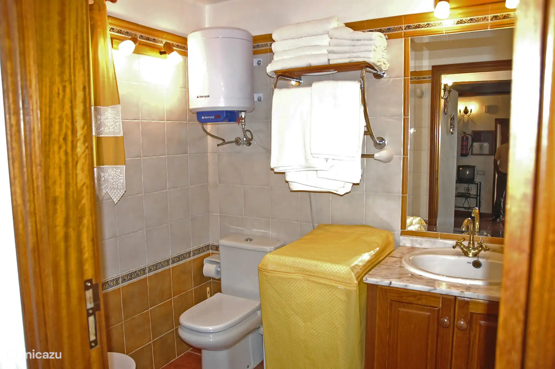 Badkamer met douche, marmeren wastafel en handdoeken; Heet water via een elektrische boiler.