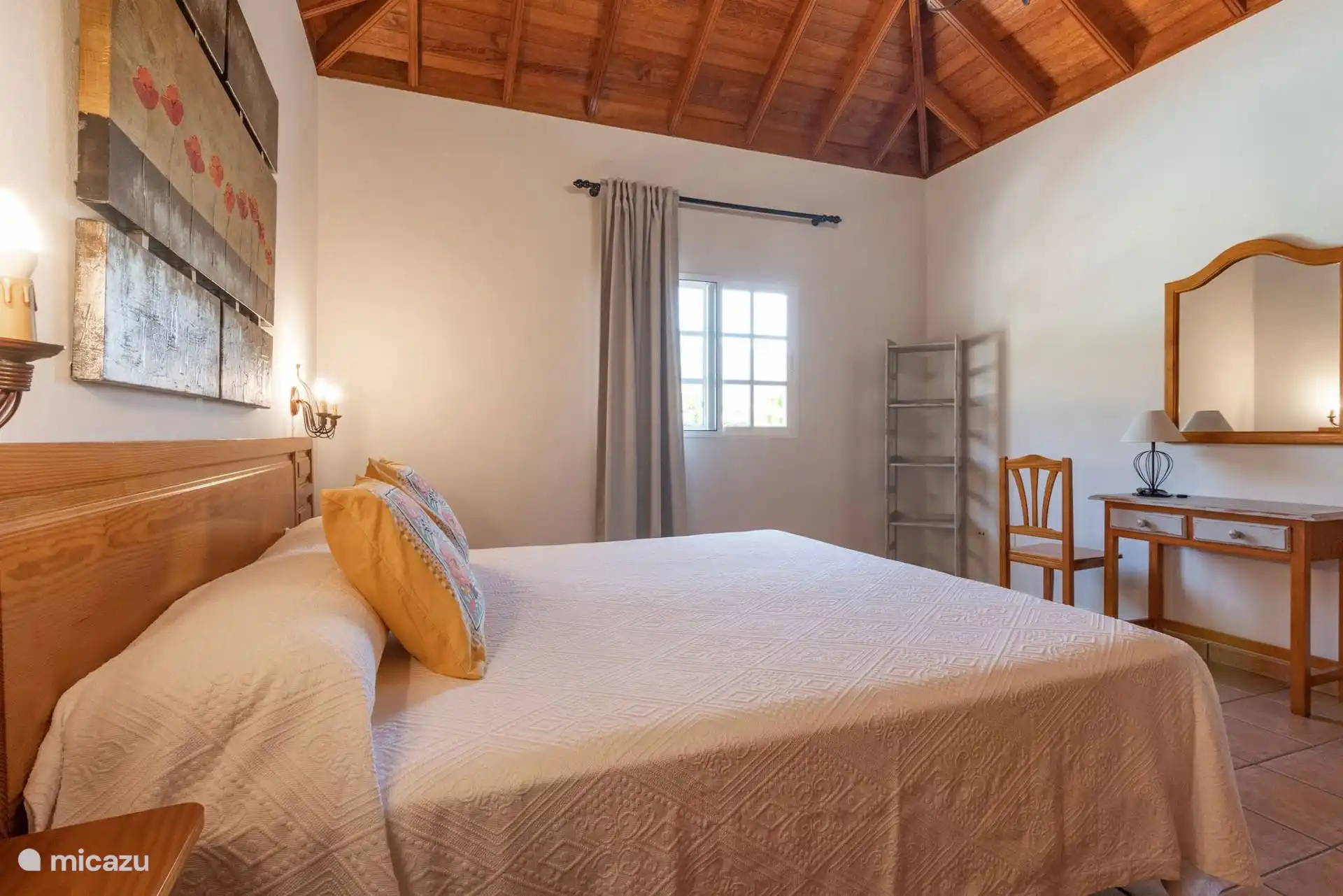 Een andere hoek van de master bedroom, met de console en spiegel, een boekenkast en het raam naar buiten.