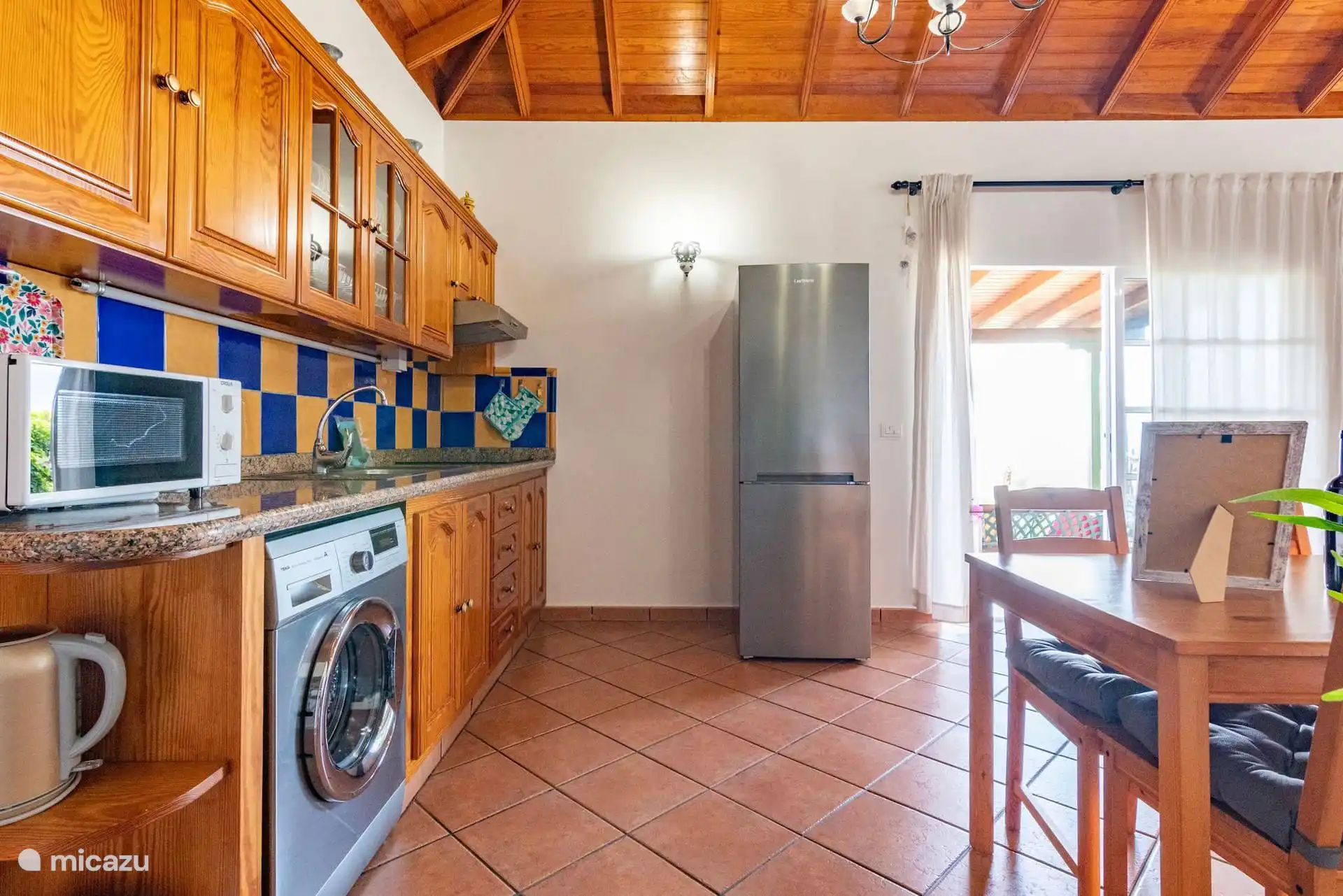 De keuken aan de andere kant: granieten aanrecht met gootsteen, magnetron en waterkoker, wasmachine onder het aanrecht en uitgang naar de veranda achterin.