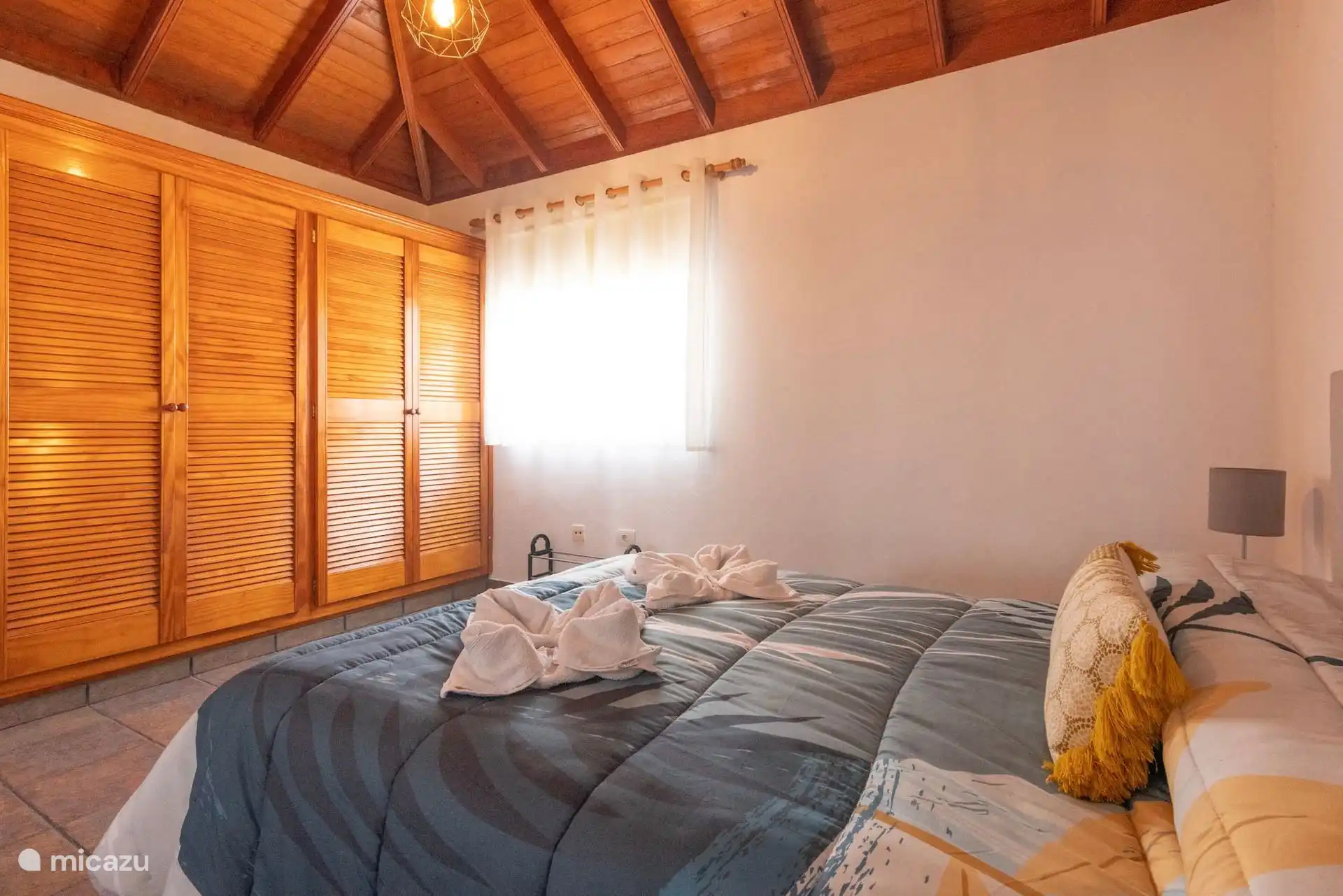 Une autre vue sur la double chambre, avec la penderie encastrée avec des portes en livrets à côté de la fenêtre.