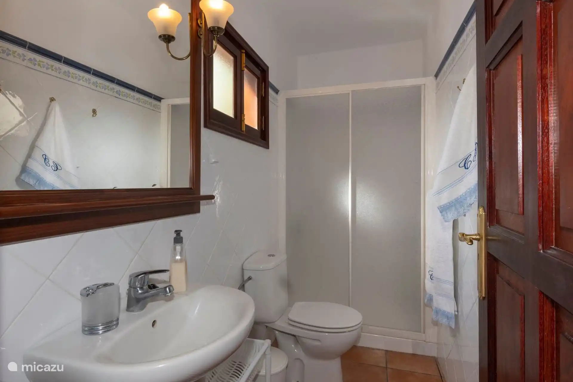 Bathroom with shower screen, sink and toilet; the towels, hung by the door.
