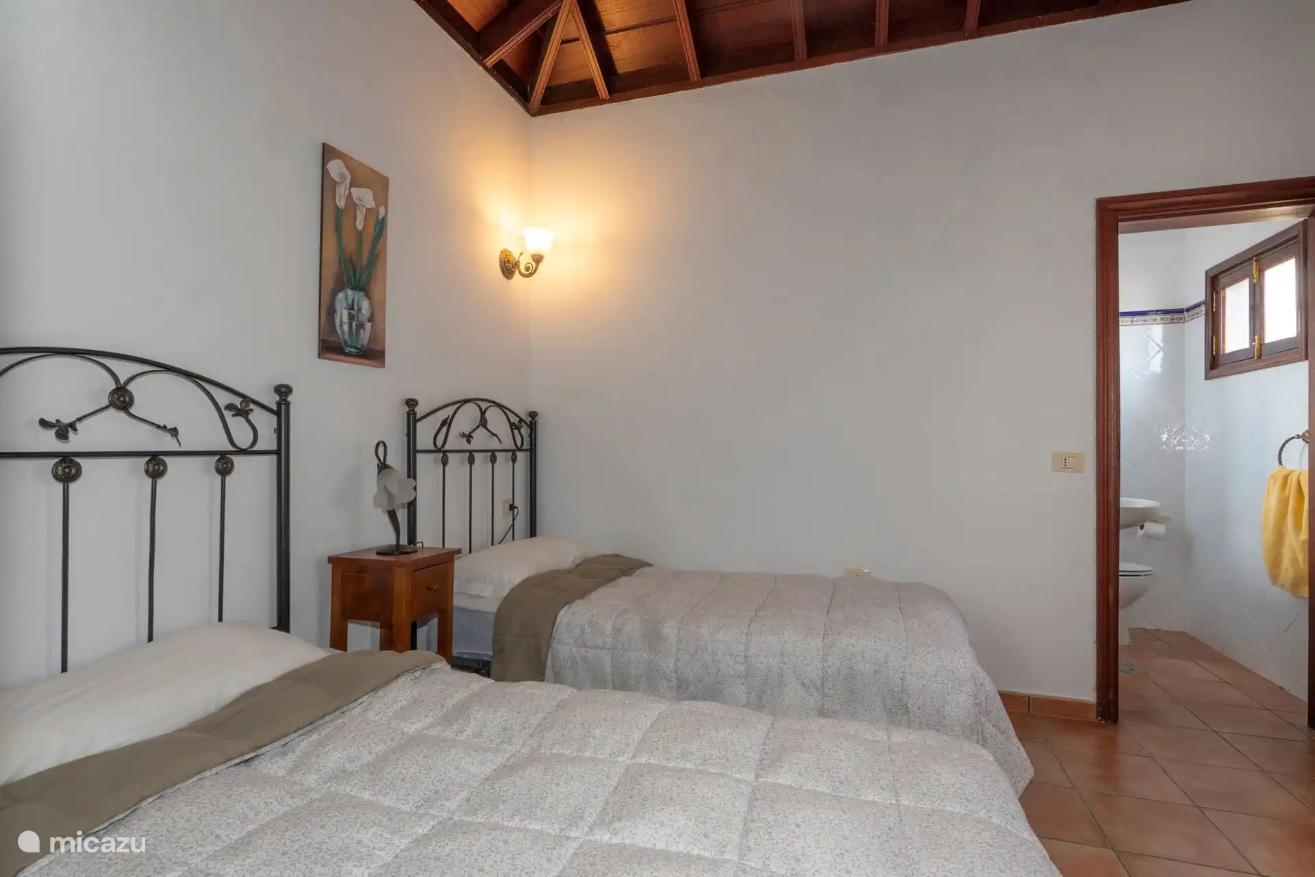 Twin bedroom under the tea-beamed ceiling; on the right, the toilet door.