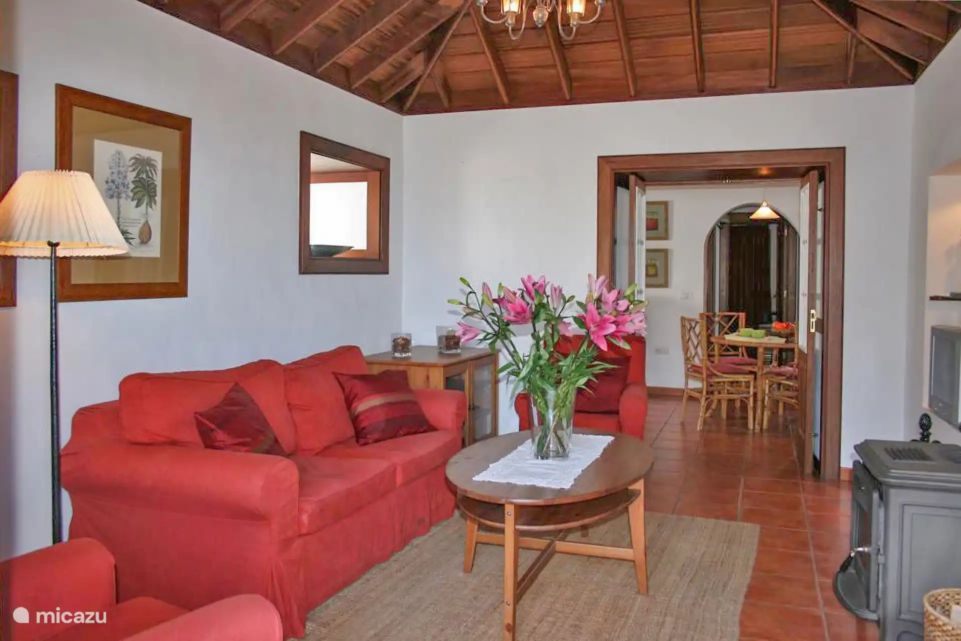Dezelfde kamer aan de andere kant; Achterin de eetkamer met rotanen stoelen en de keuken.