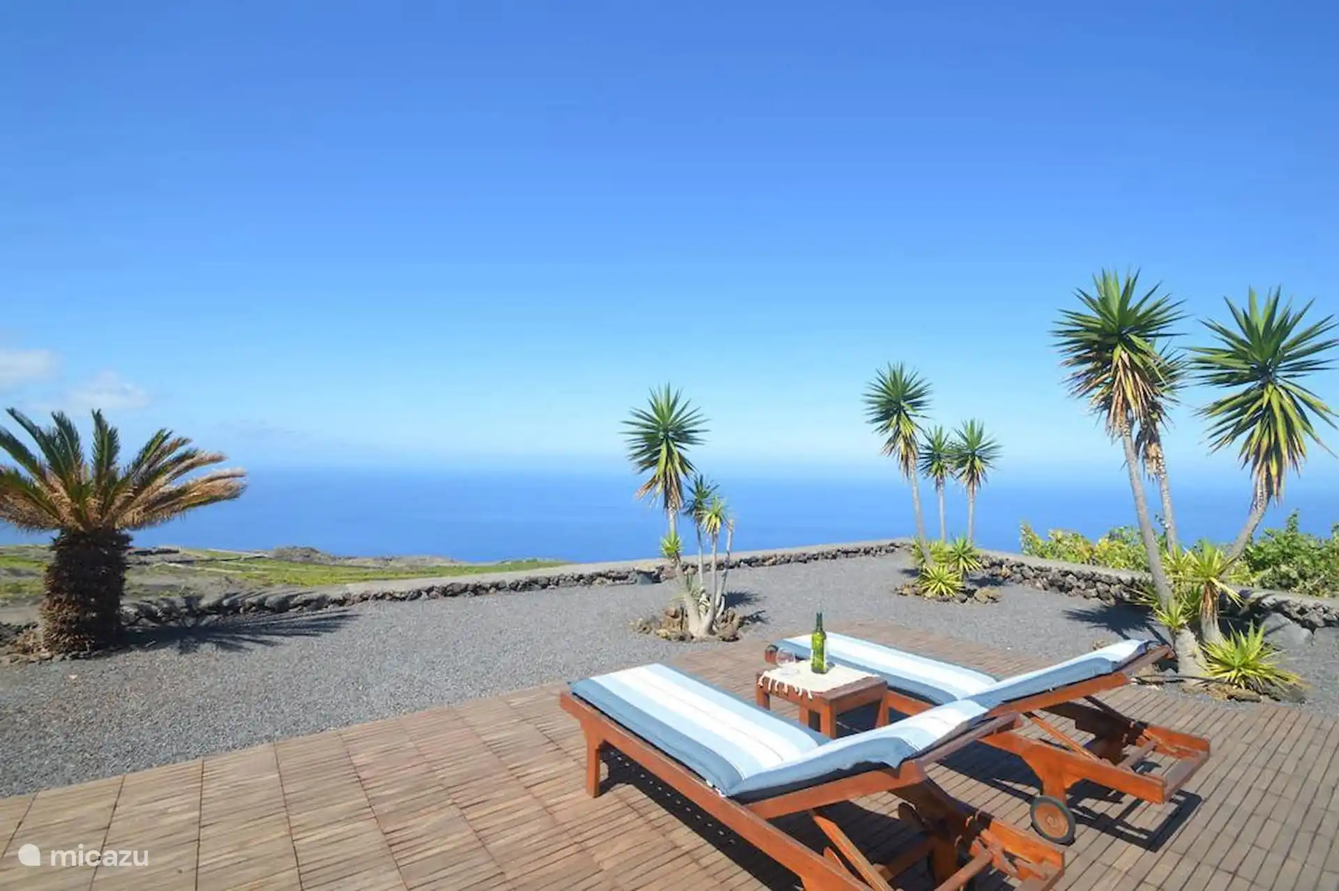 The sun loungers and their small table on the stage, with the picón, the dracenas and the sea occupying the entire horizon.