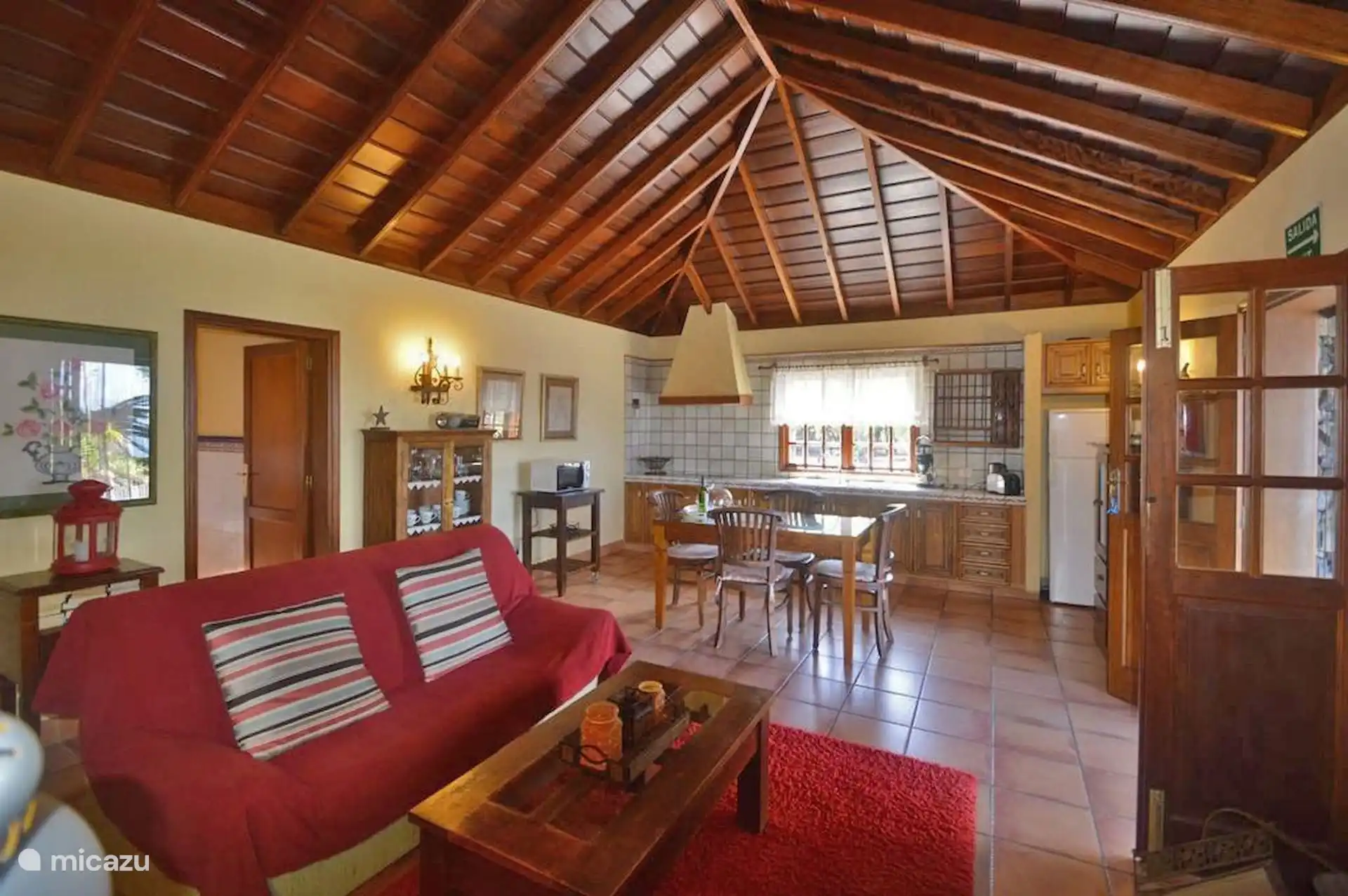 Another view of the living room, with the open kitchen at the back: hood, wooden countertop, fridge and the dining table between the two spaces.