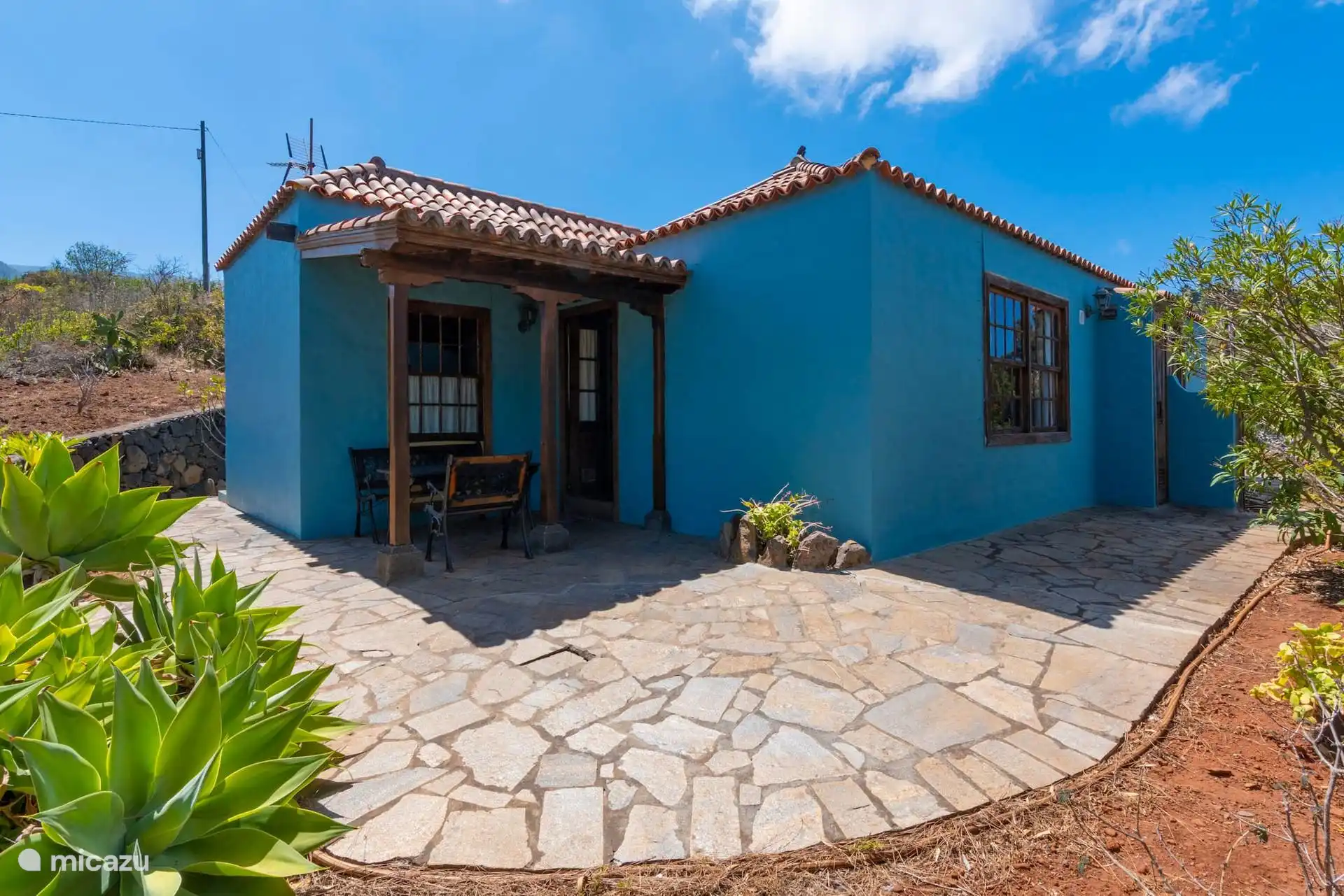 The house on the outside: blue façade, Arabic tile and the covered terrace over the courtyard of stone slabs.