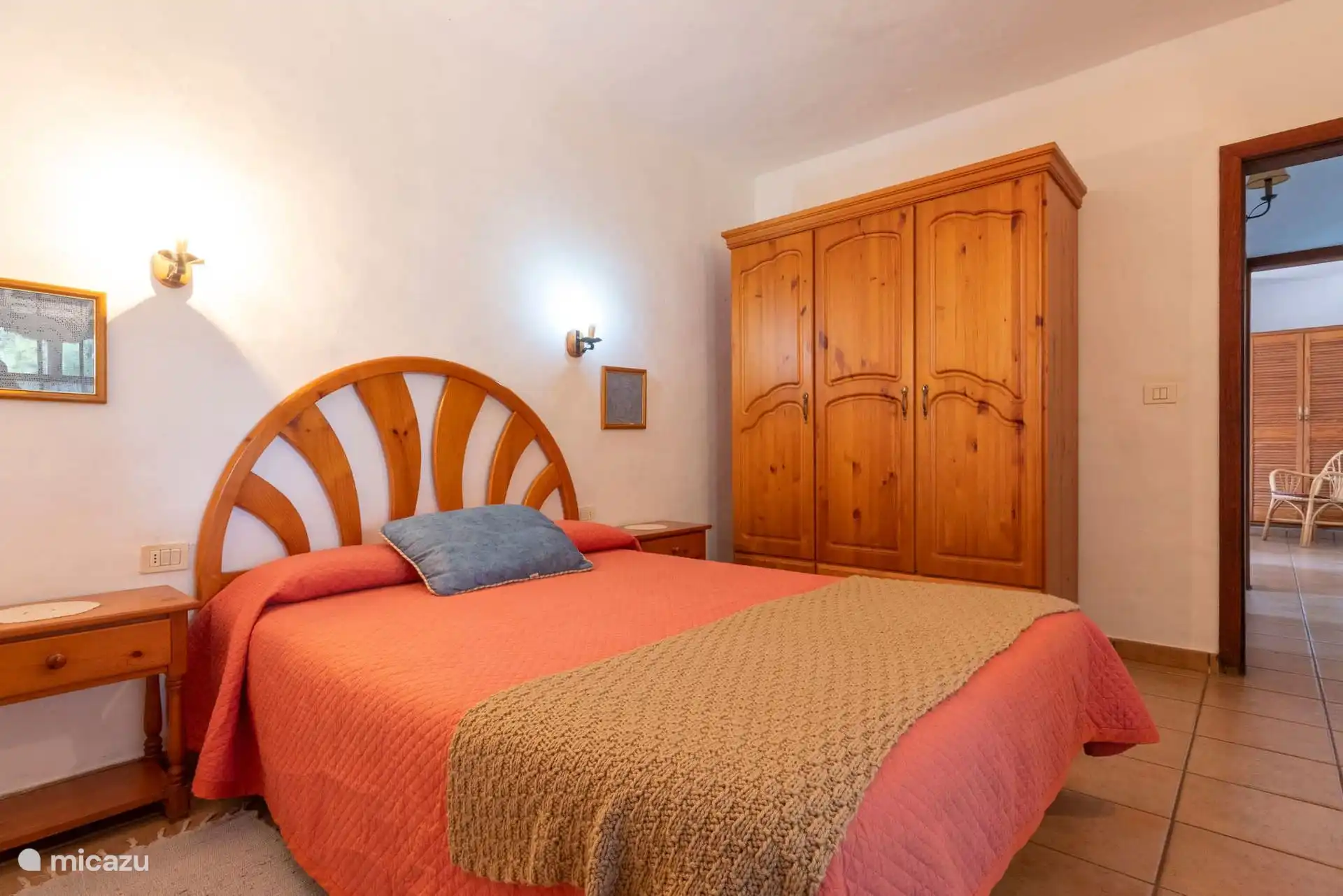 Bedroom with double bed, fanned wooden headboard and three-door pine wardrobe.