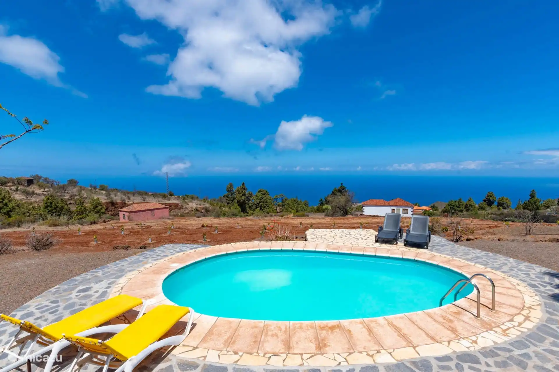 Another view of the pool, with sun loungers on both sides and the newly planted land going down towards the sea.