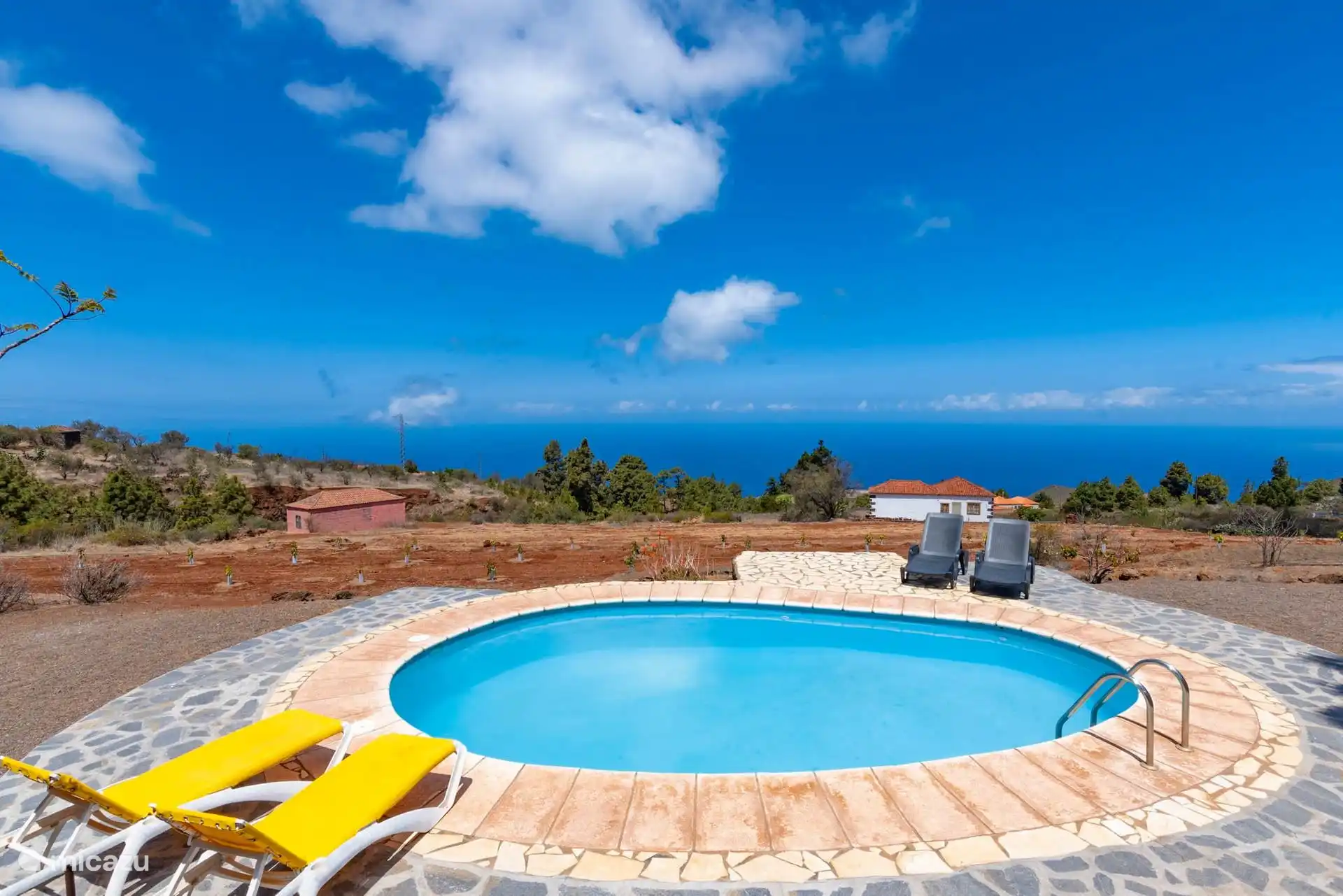 Das Schwimmbecken ist zum Meer hin offen, mit dem neu bepflanzten Land der Finca im Hintergrund.