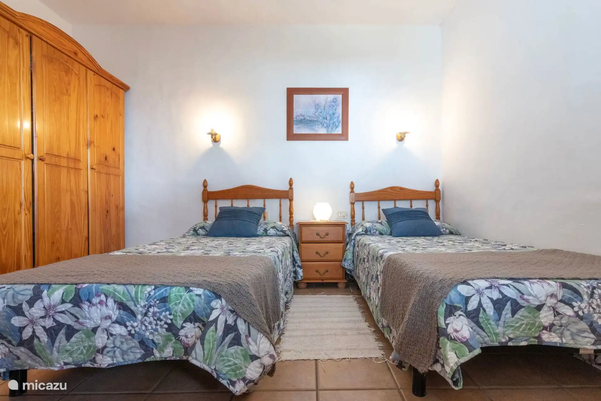 Schlafzimmer mit zwei Einzelbetten, Nachttisch dazwischen und Holzkleiderschrank.