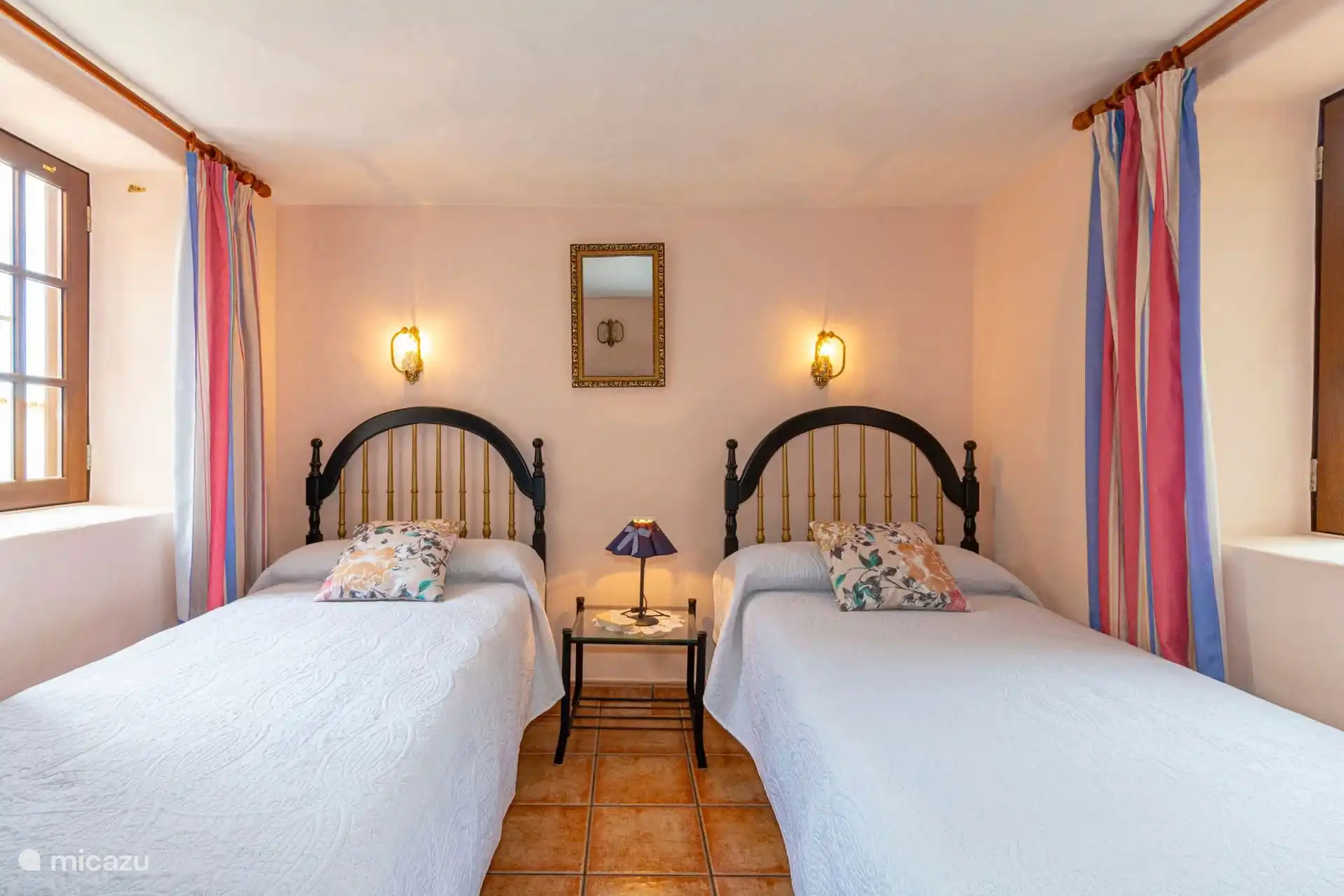The same bedroom from the foot of the beds, with the glass bedside table in the middle and the window on one side.