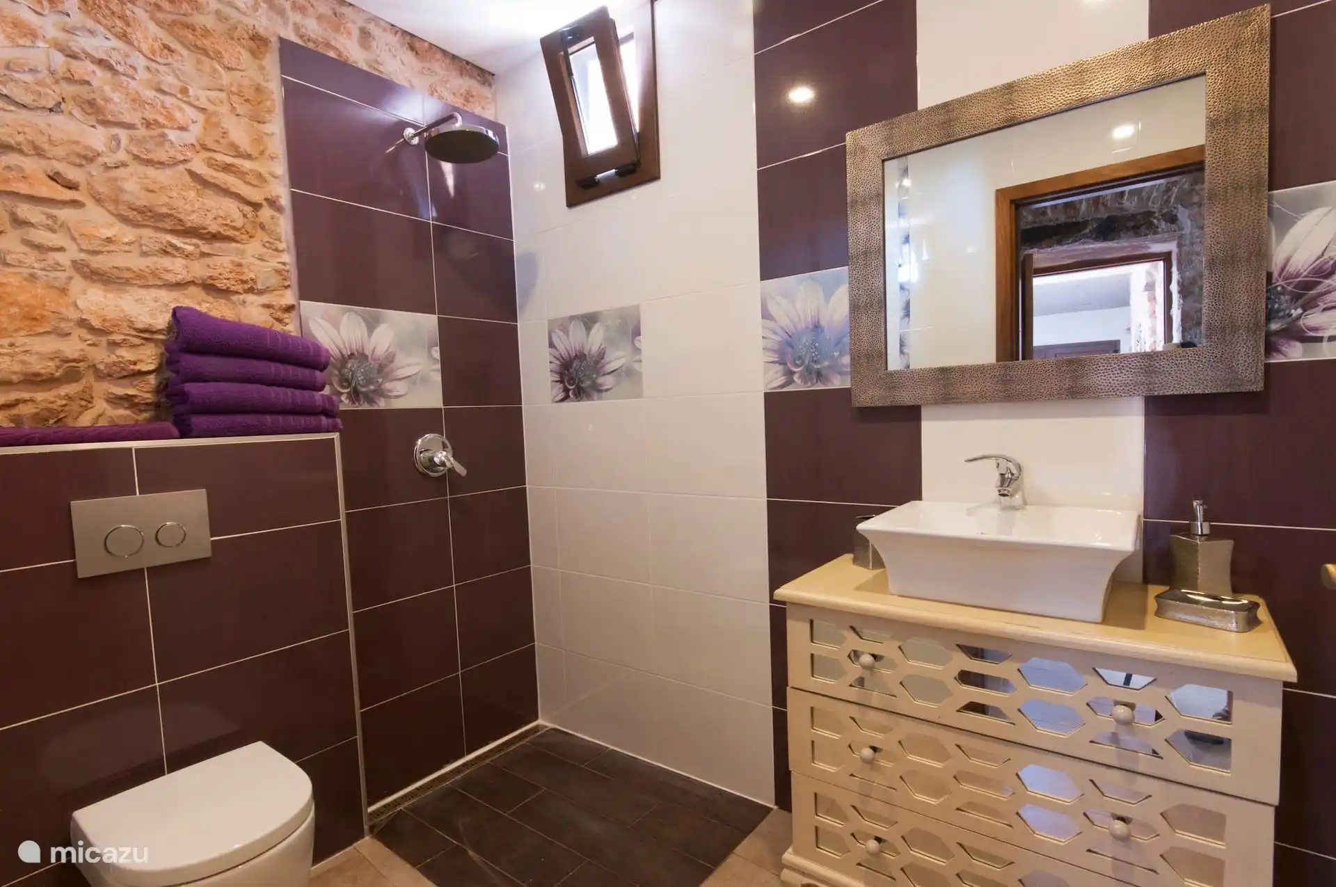 Bathroom with walk-in shower, washbasin on chest of drawers and an exposed stone canvas.