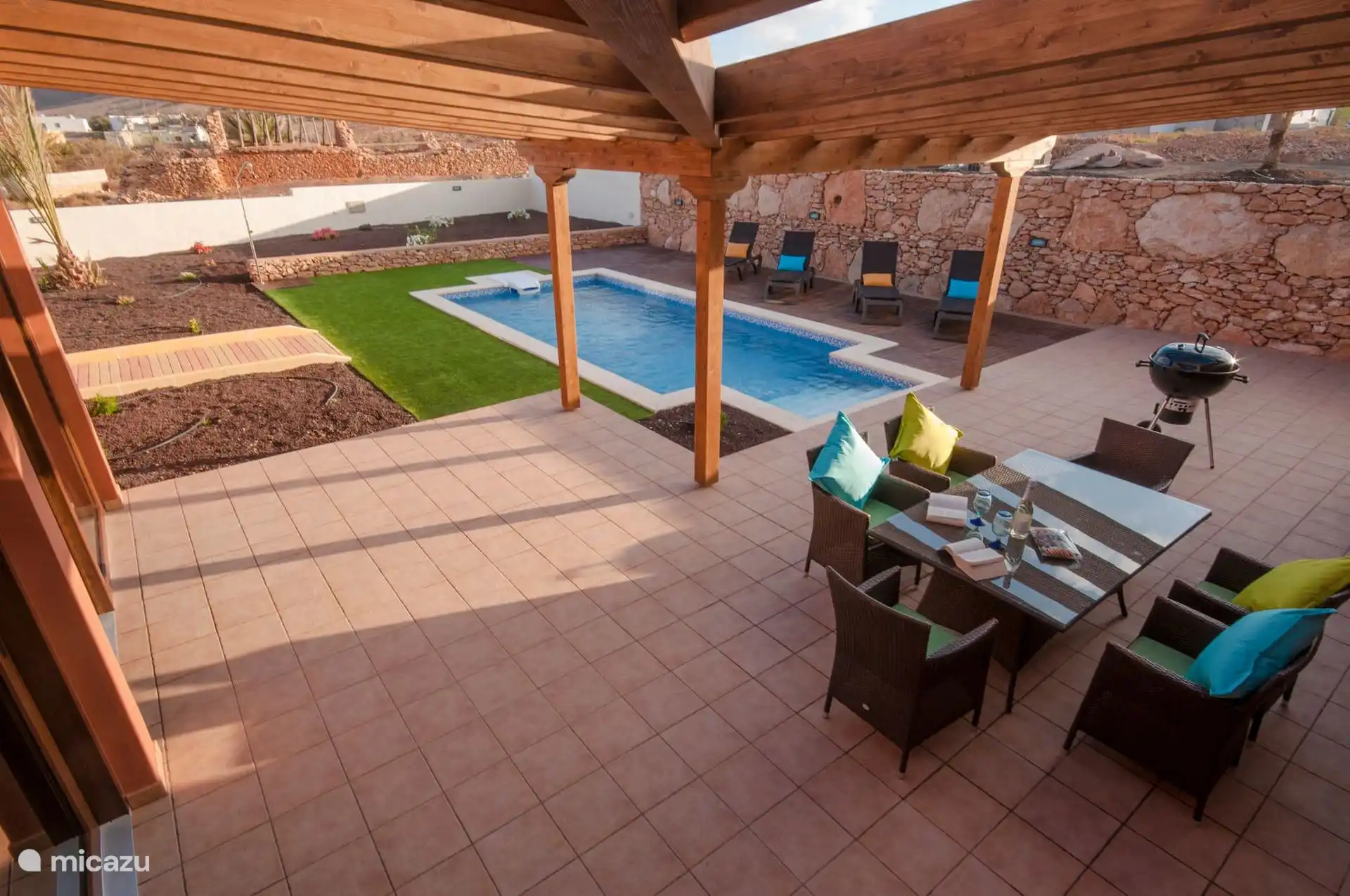 The terrace and pool seen from the house: table, barbecue, sun loungers and the dry stone wall that encloses the plot.