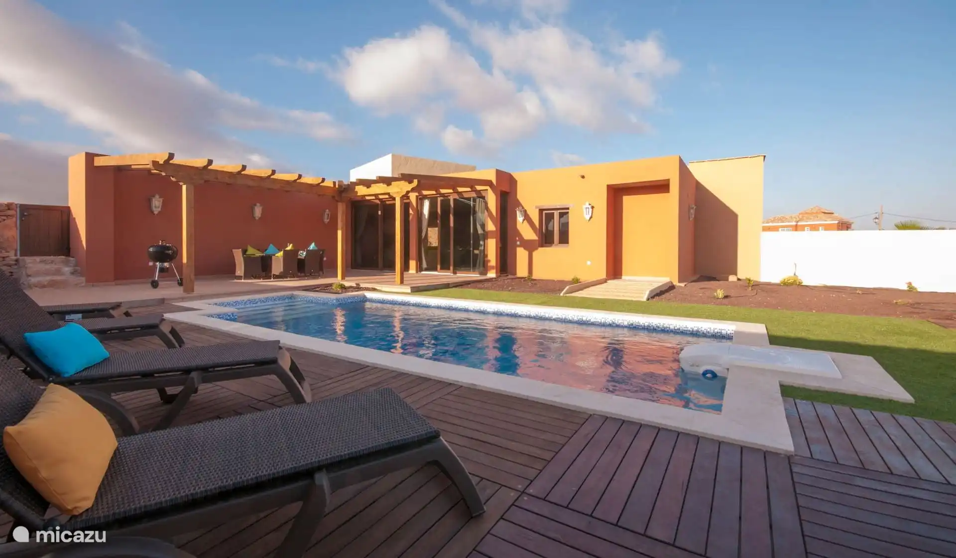 The house seen from the solarium: swimming pool with wooden decking, sun loungers and, under the pergola, the dining table next to the barbecue.