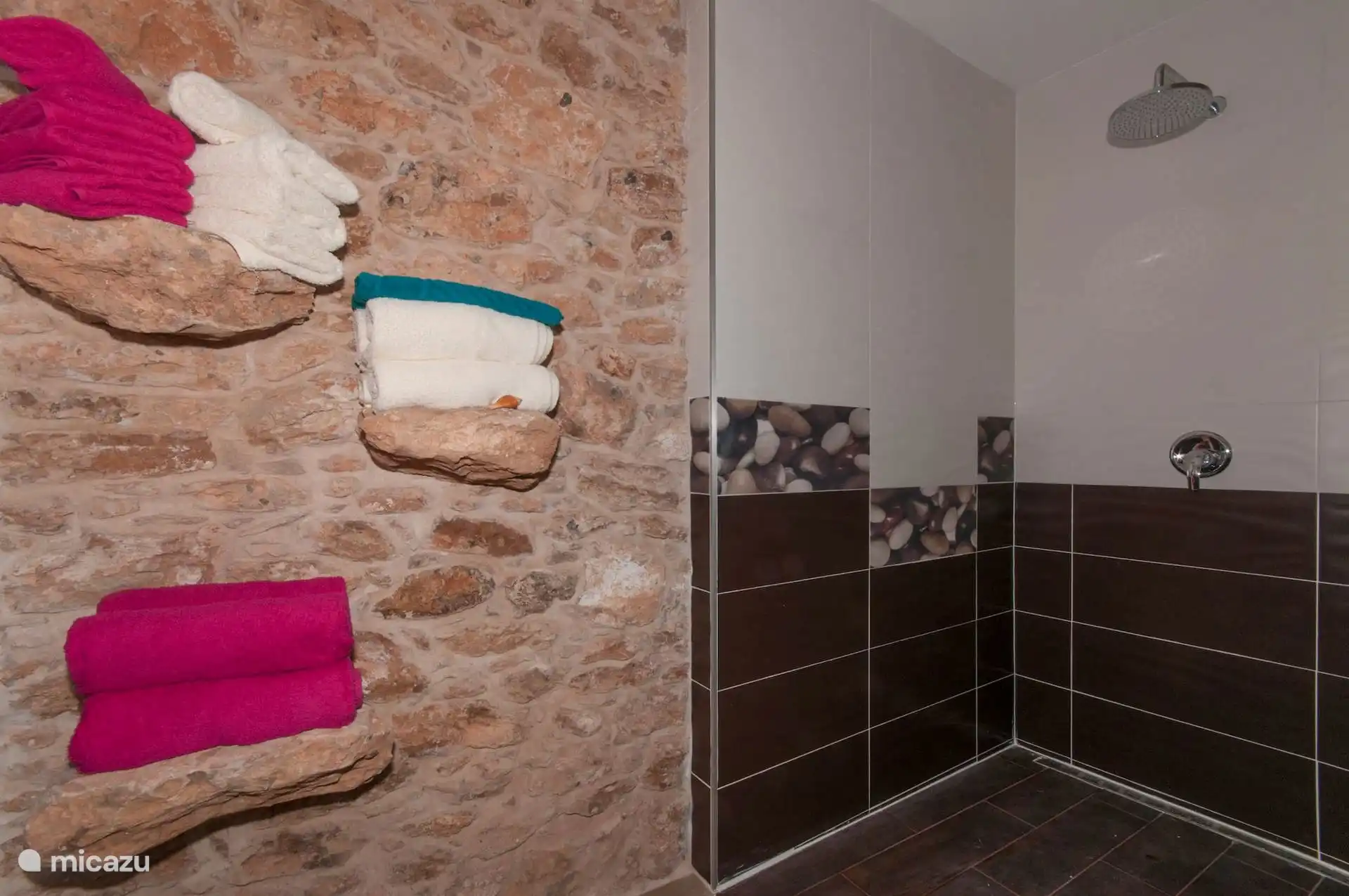 Shower detail: rain spray and towels on stone shelves embedded in the wall.