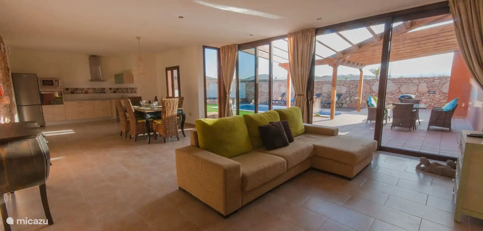 The living room is open to the dining room and the kitchen; The windows overlook the terrace and the pool.