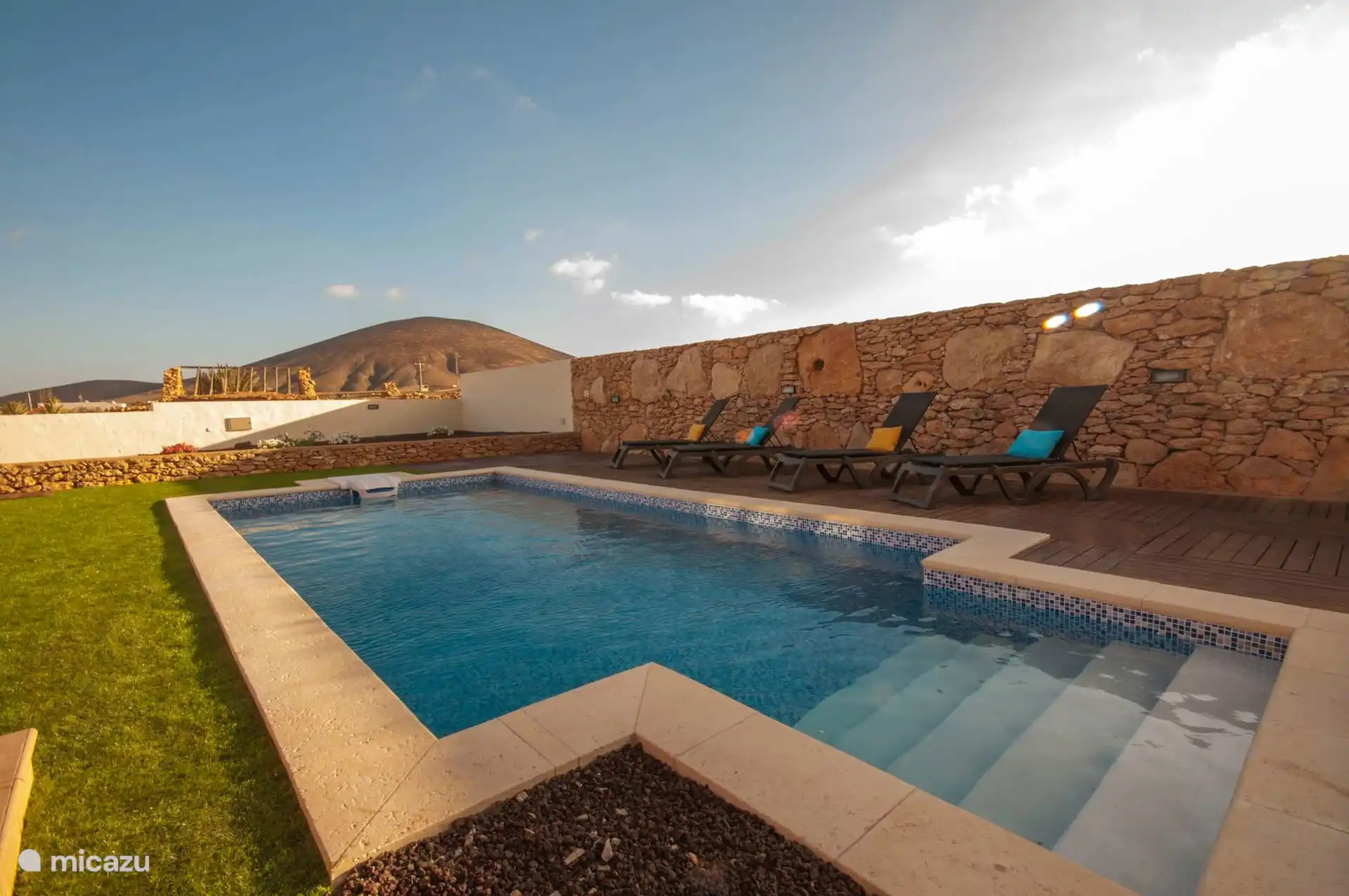The pool from the other end, with the sun loungers on the platform and the mountain in the background.