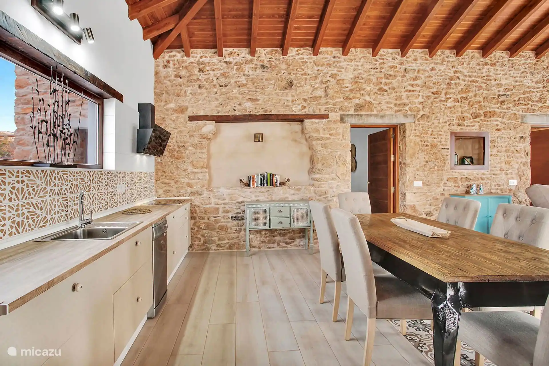 Cocina en línea con fregadero, vitrocerámica y lavavajillas; al lado, la mesa de comedor y el aparador verde.