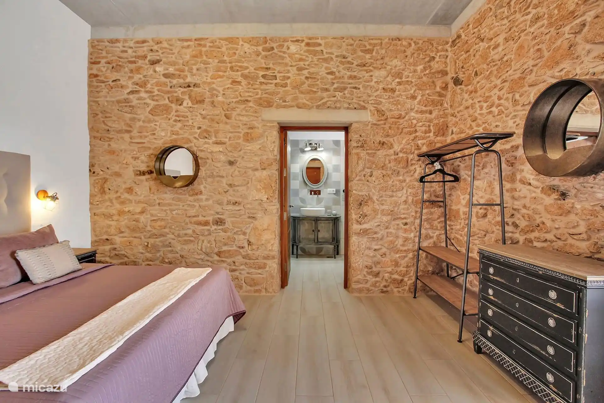 El mismo dormitorio hacia su baño en suite, con el burro de ropa y la cómoda junto a la pared de piedra.