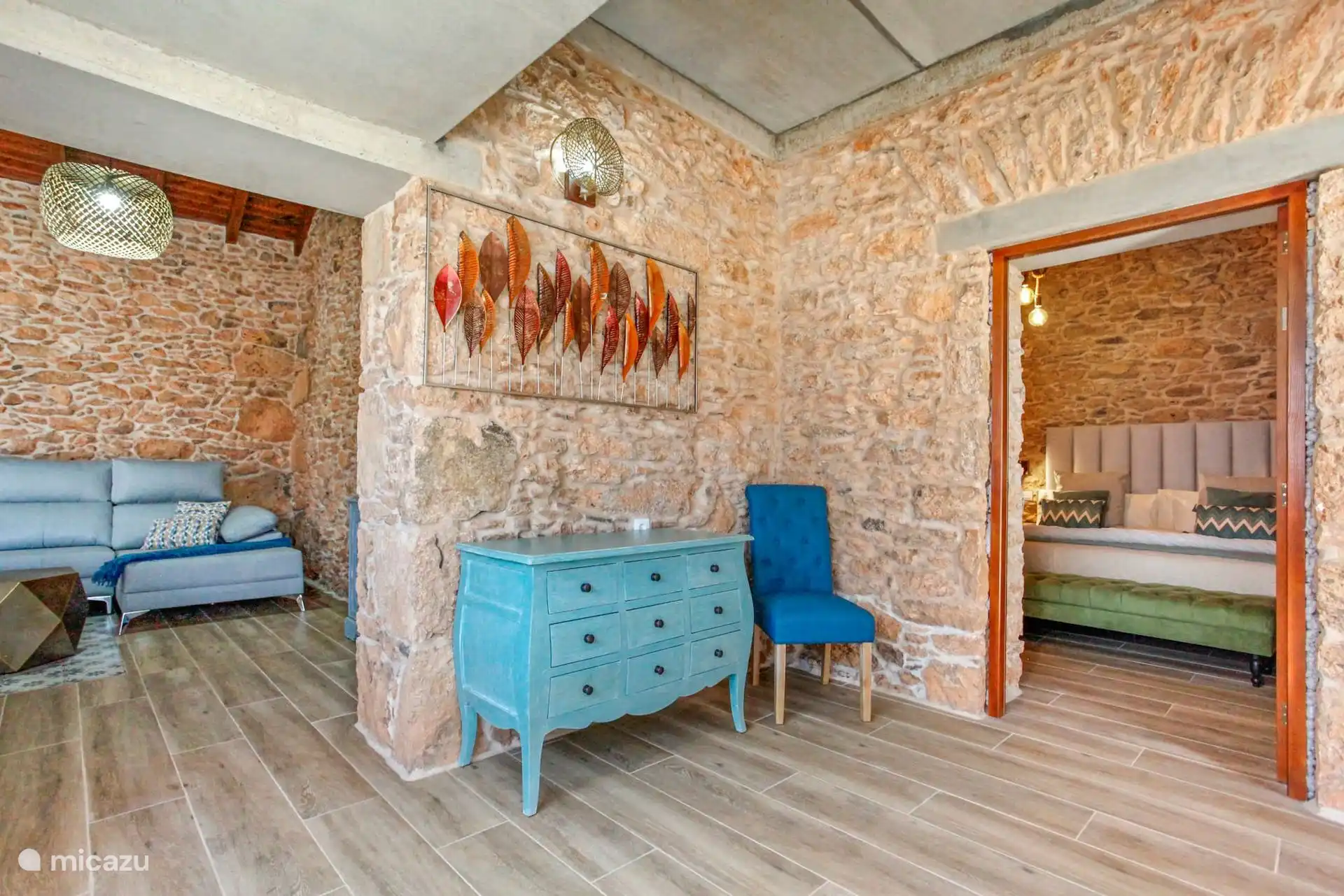 Doorgang met turquoise ladekast en gestoffeerde stoel; Aan de ene kant is de woonkamer en aan de andere kant de deur naar een slaapkamer.