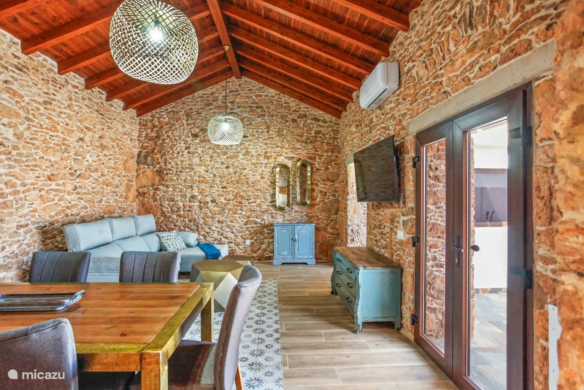 De woonkamer vanaf de eettafel, met de bank, de turquoise ladekast en de glazen deur naar het terras.