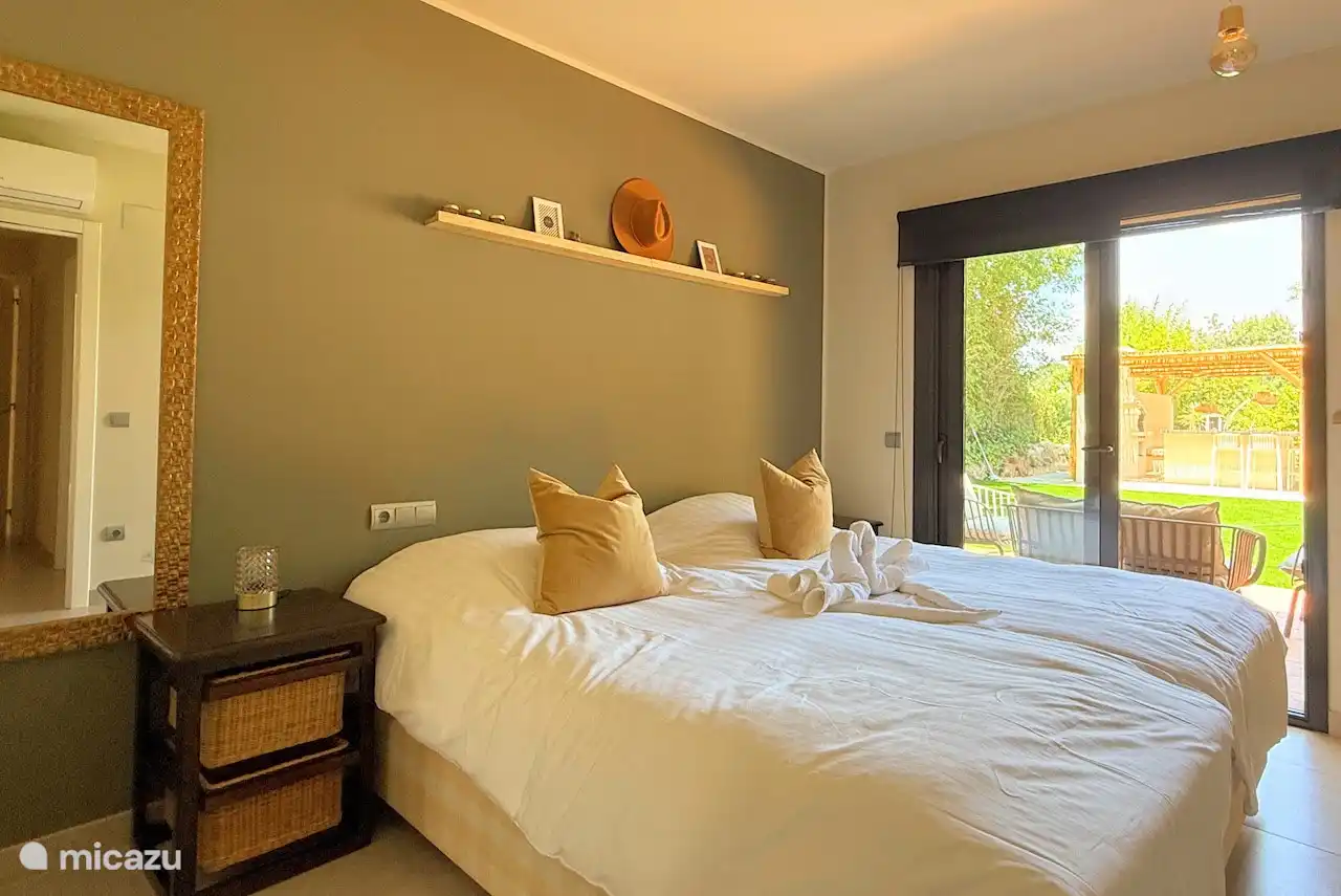 Ruime master bedroom en suite met terras aan de zijkant bij de tuin.