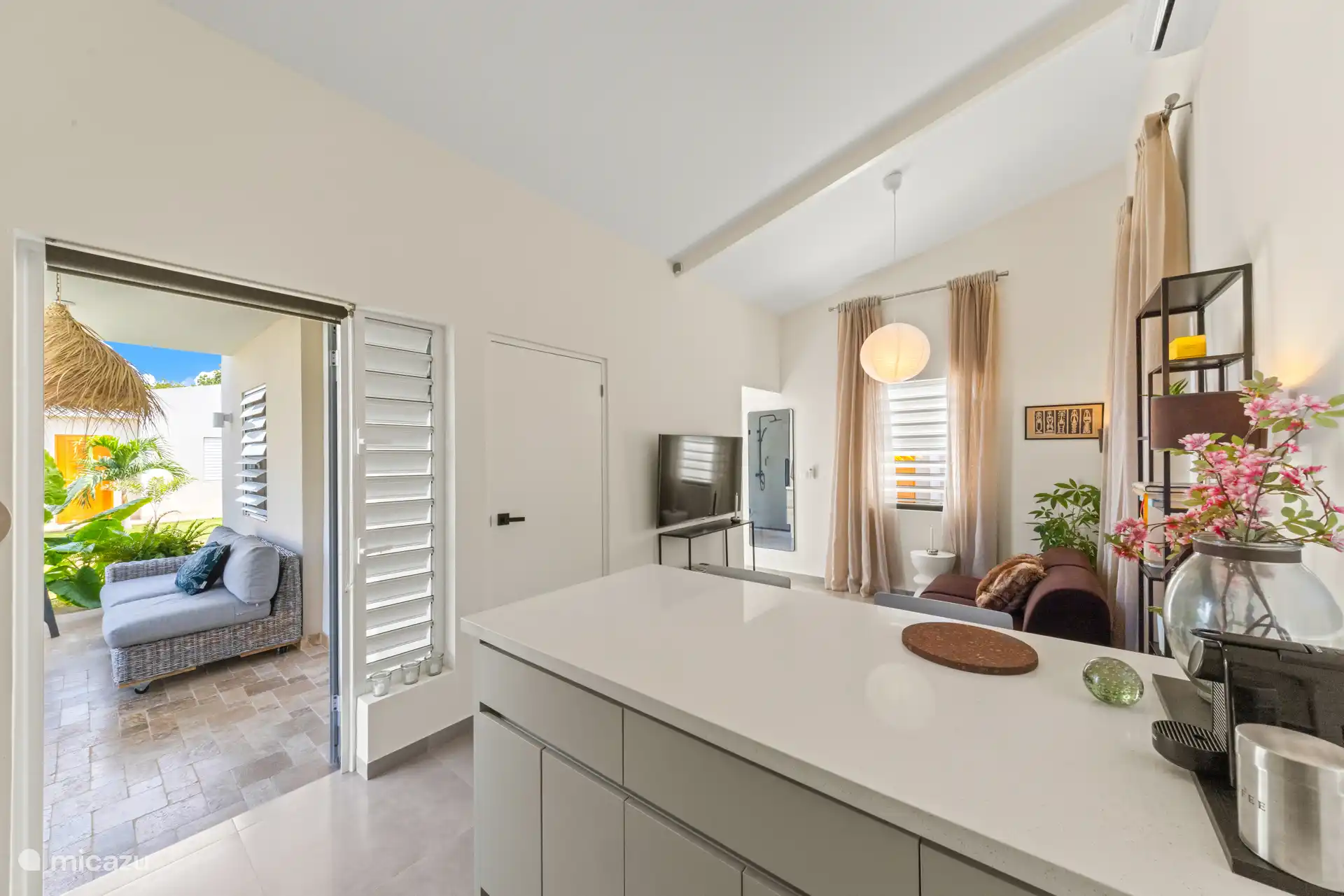 Een overzicht van de gezellige leefruimte met open keuken, comfortabele zithoek en het fijne buitenzitje. Binnen en buiten lopen mooi in elkaar over – perfect voor een ontspannen verblijf op Curaçao