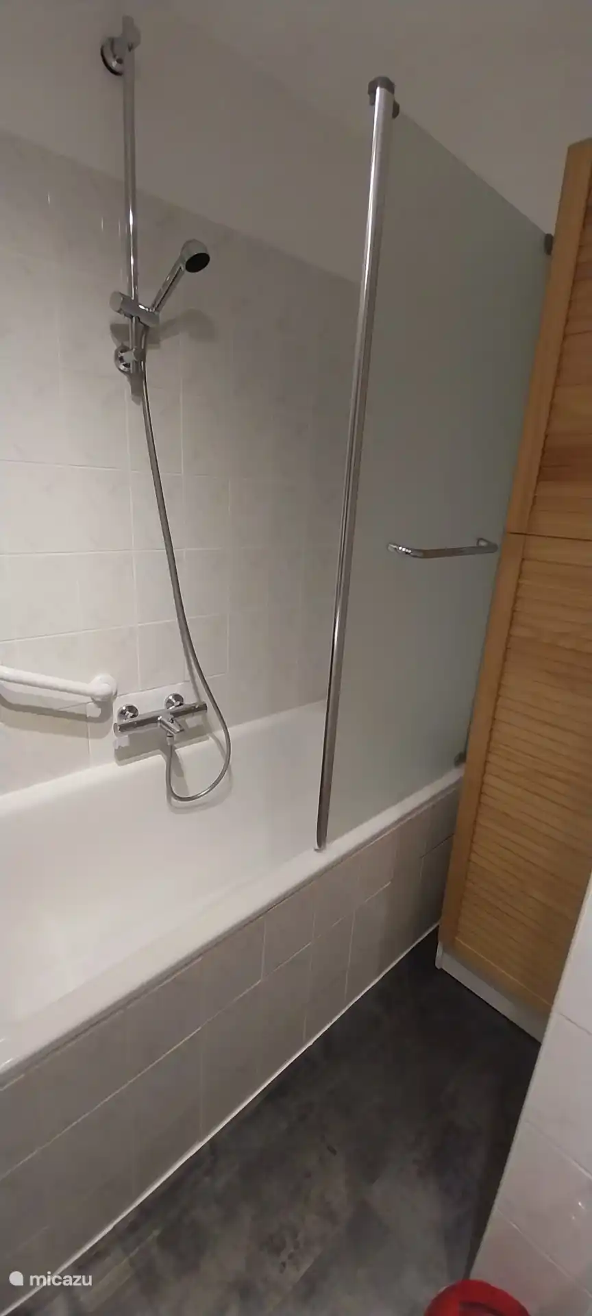 Space bathtub with glass shower screen, safety handle and wooden storage for a moment of relaxation in complete serenity.