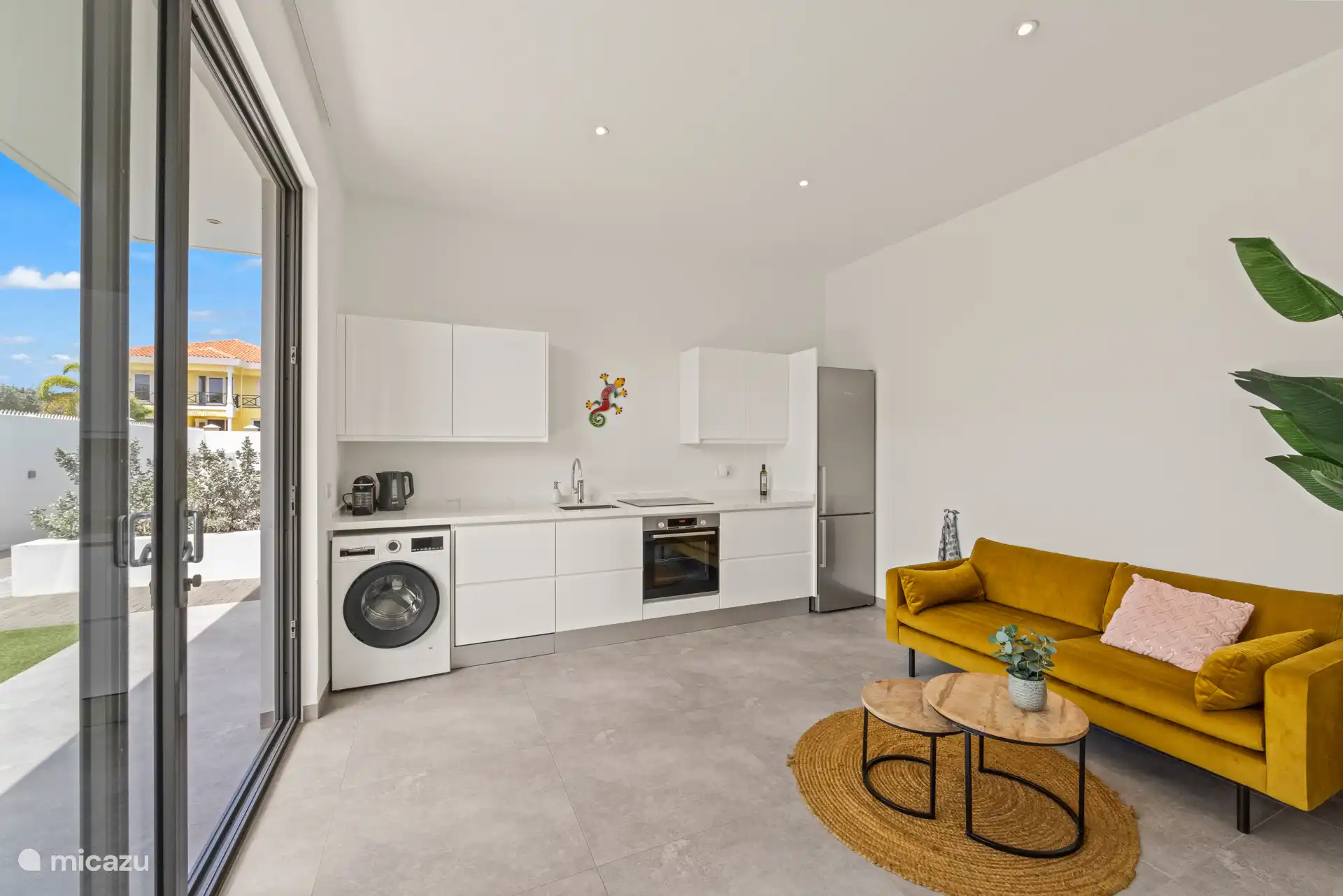 Binnen vindt u een gezellige woonkamer met een comfortabele bank en een open keuken, volledig uitgerust met moderne apparatuur zoals een koelkast, oven, vaatwasser, wasmachine en koffiezetapparaat.