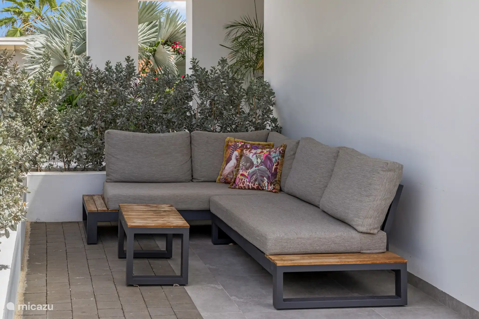 Buiten staat een loungebank onder een schaduwdoek.
