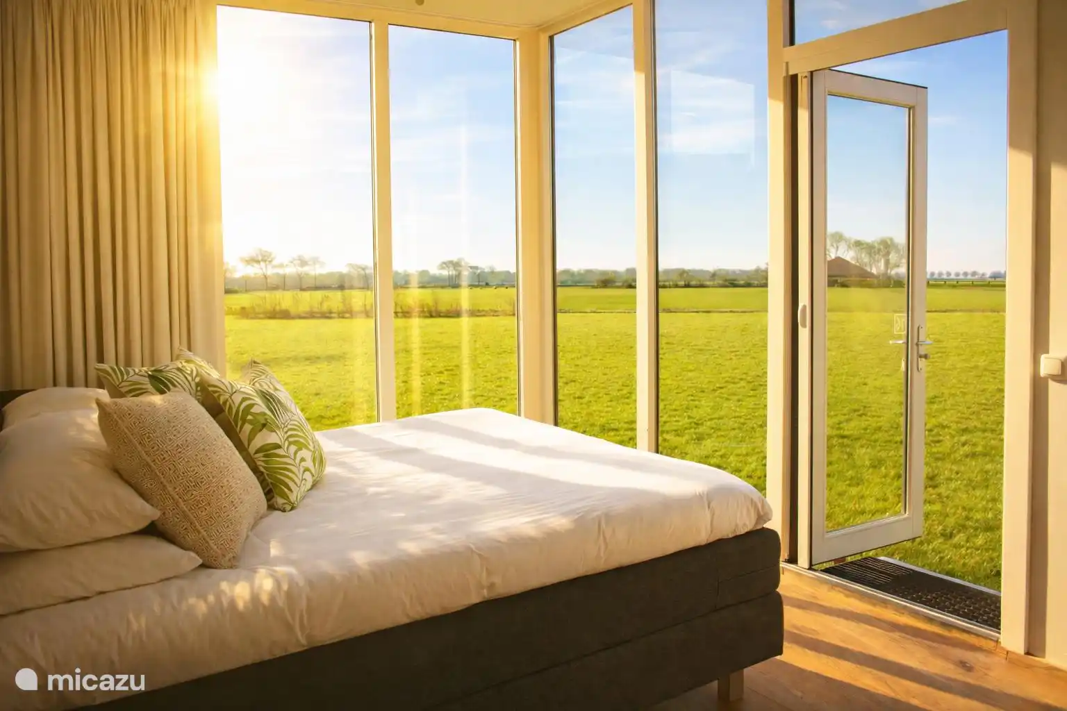 Openslaande deuren naast het bed, zo het weiland in