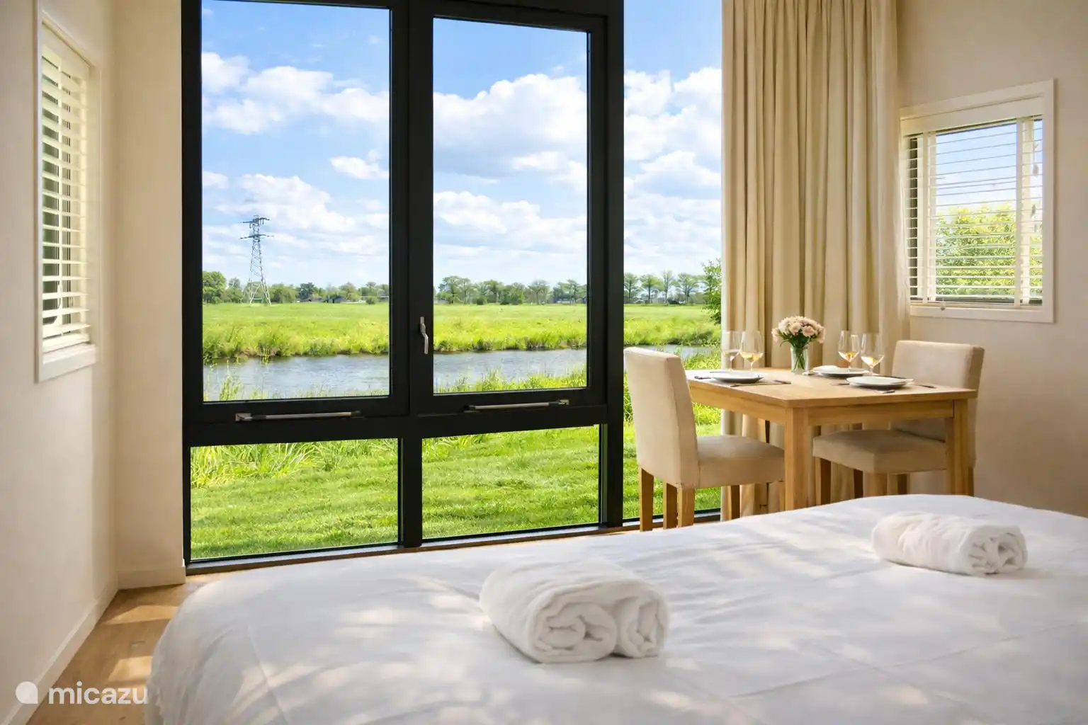 Opgemaakt bed met verse handdoeken bij het raam