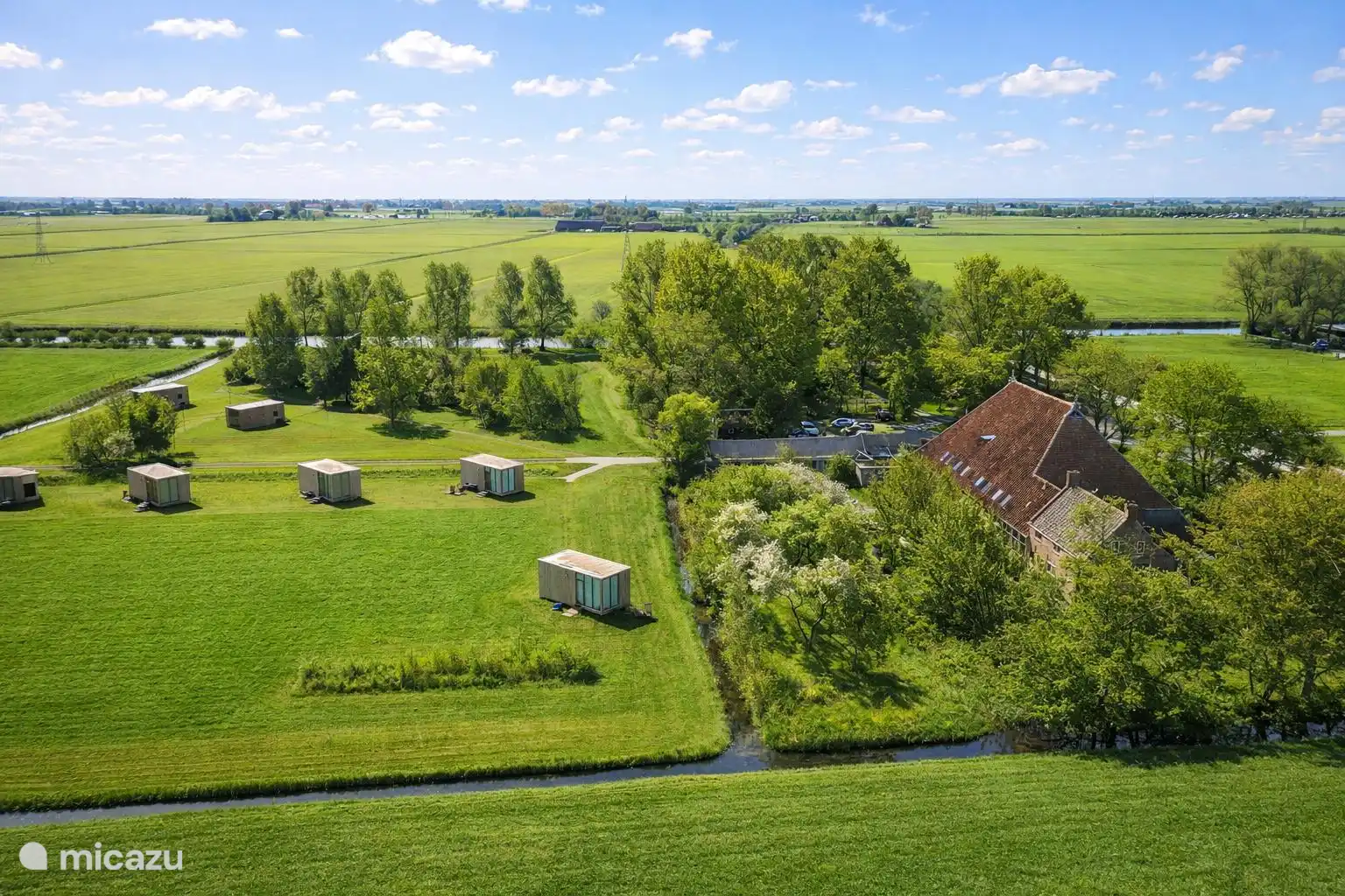 Luchtfoto van het weiland met de weidesuites en de boerderij