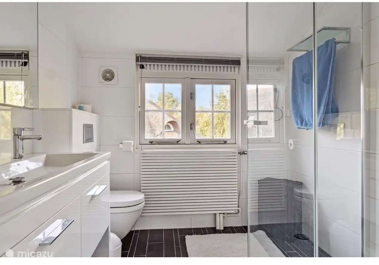 El baño de la planta baja tiene ducha, dos lavabos, un inodoro y un perchero.