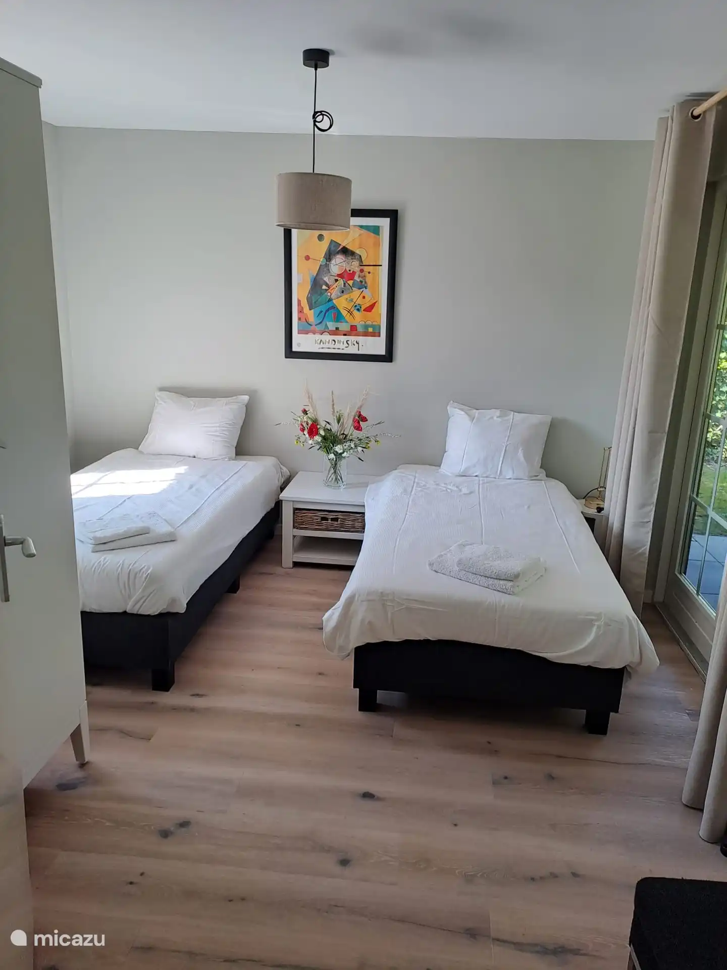 Primer dormitorio en la planta baja, con vistas al jardín.  Las dos camas miden 100 x 200 cm. Hay un armario grande y dos mesas.